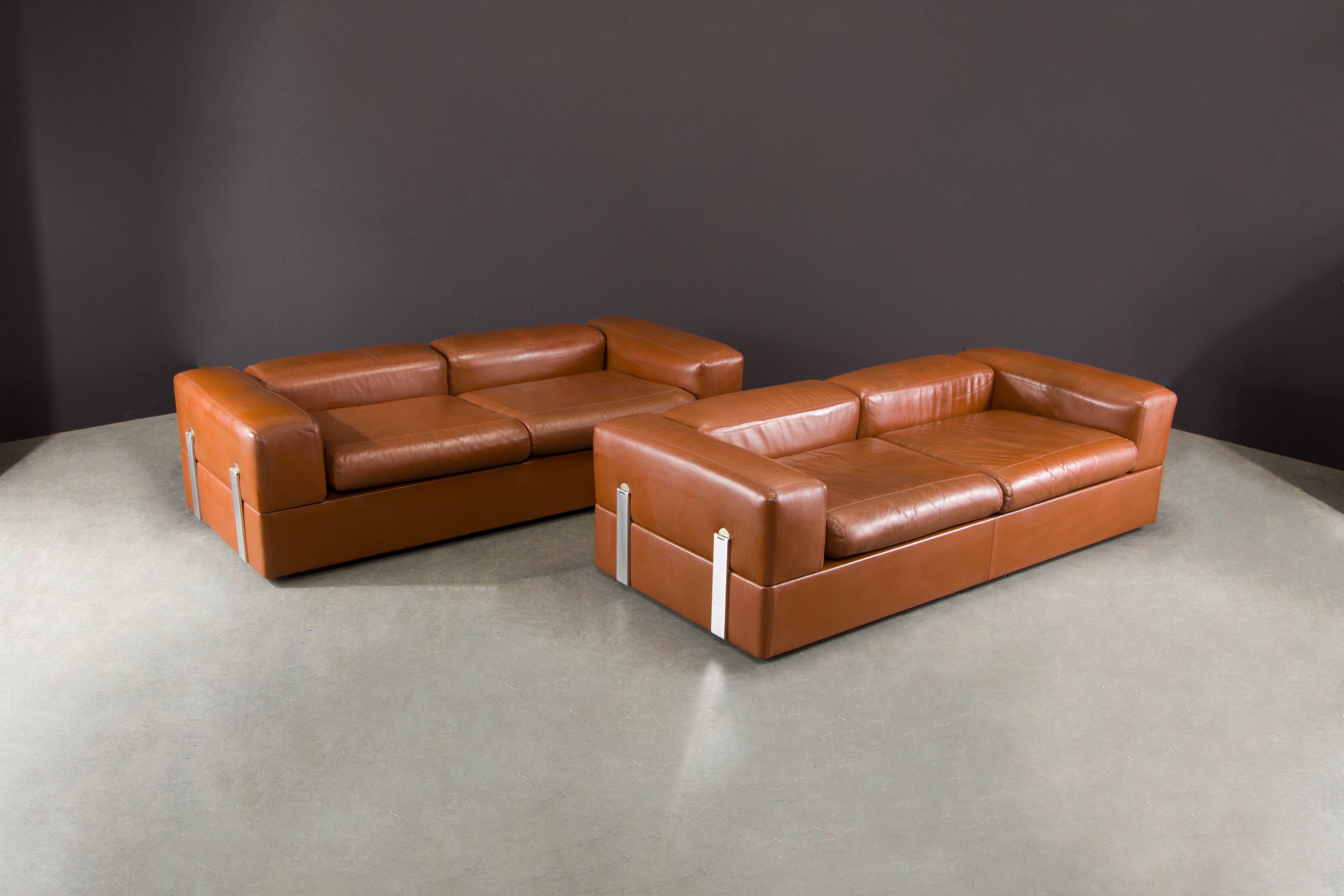 This pair of rare and sought-after Model #711 convertible sofas / beds by Tito Agnoli for Cinova, circa 1960s, feature sumptuous cognac leather, sleek steel hardware and built-in white laminated side tables. This innovative design transforms from a