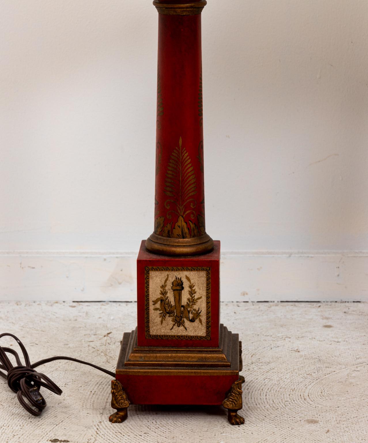 Pair of Chinoiserie style tole table lamps with column shaped body on a plinth base. The lamp is further painted with motifs of anthemions on the column and a flaming torch framed by Roman laurel wreaths on the base. Shades not included. Please note