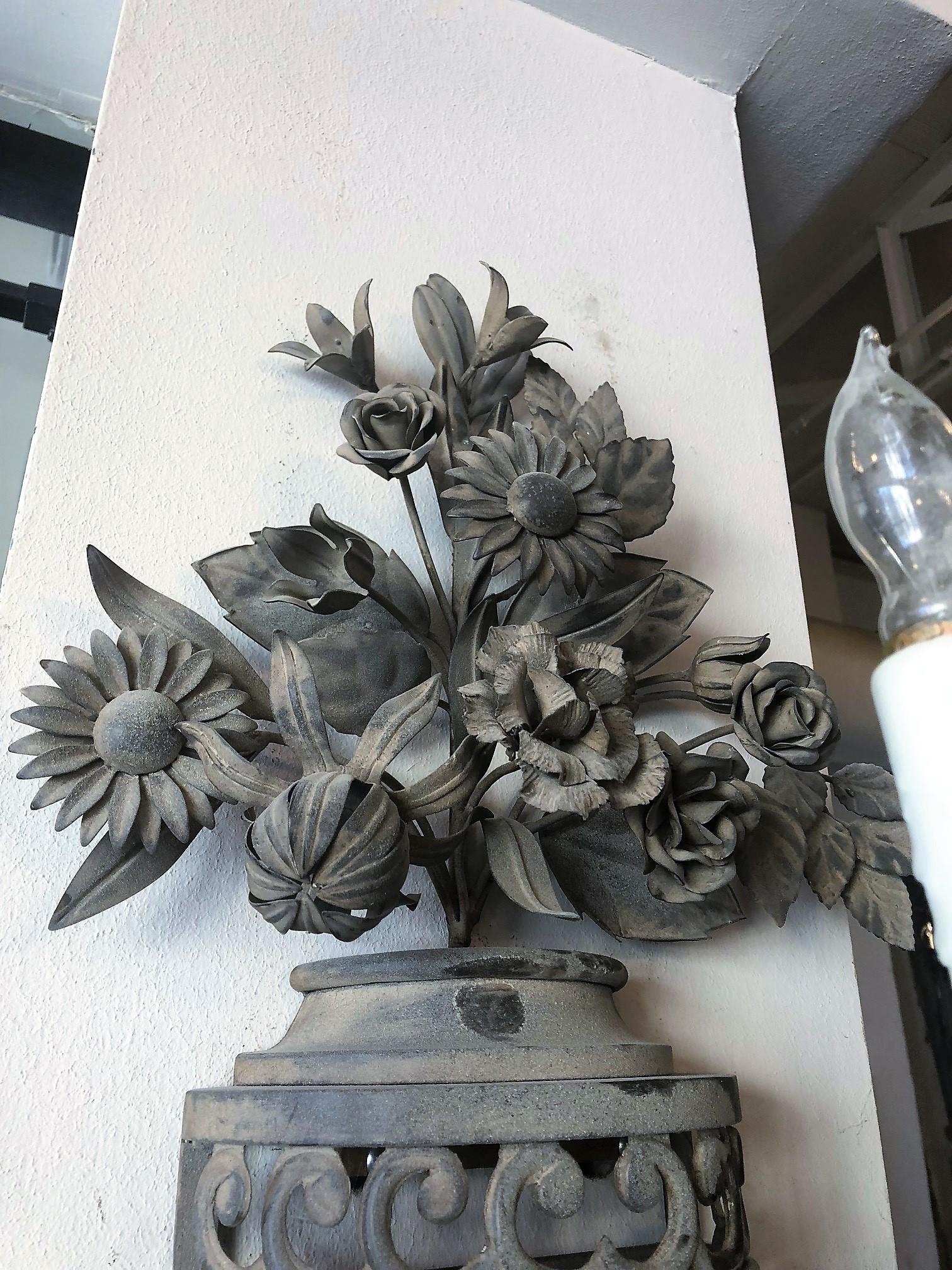 This pair of mixed metal outdoor wall sconces are adorned with flowers, acanthus leaves, and a cluster of grapes at the base. 

Origin France,

circa 1940

Measurements:
25