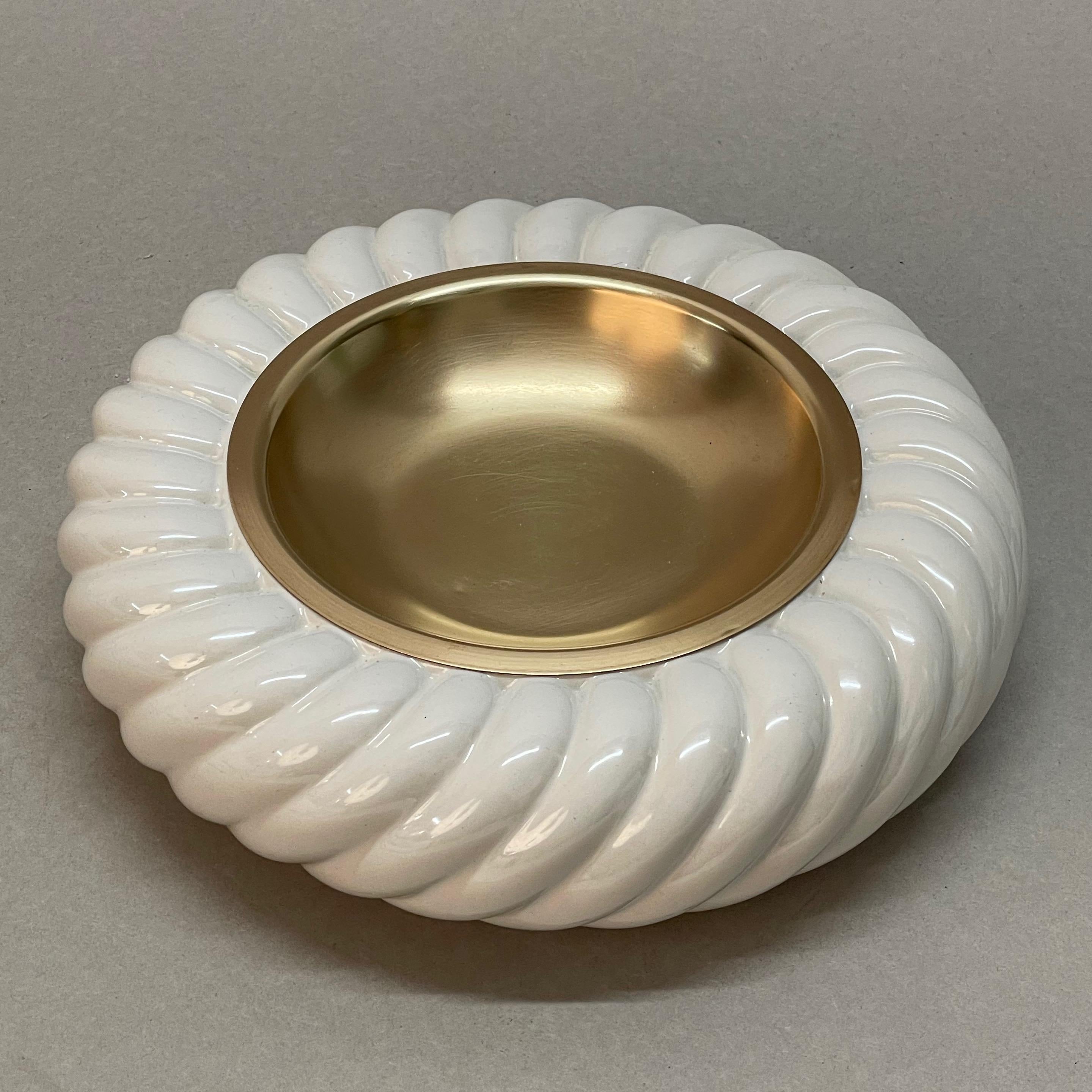 Incredible pair of Mid-Century Modern white ceramic and brass ashtrays. These fantastic pieces were designed by Tommaso Barbi and produced by B. Ceramiche in the late 1960s in Italy.

The manufacturer's brand stamp is at the bottom of the items