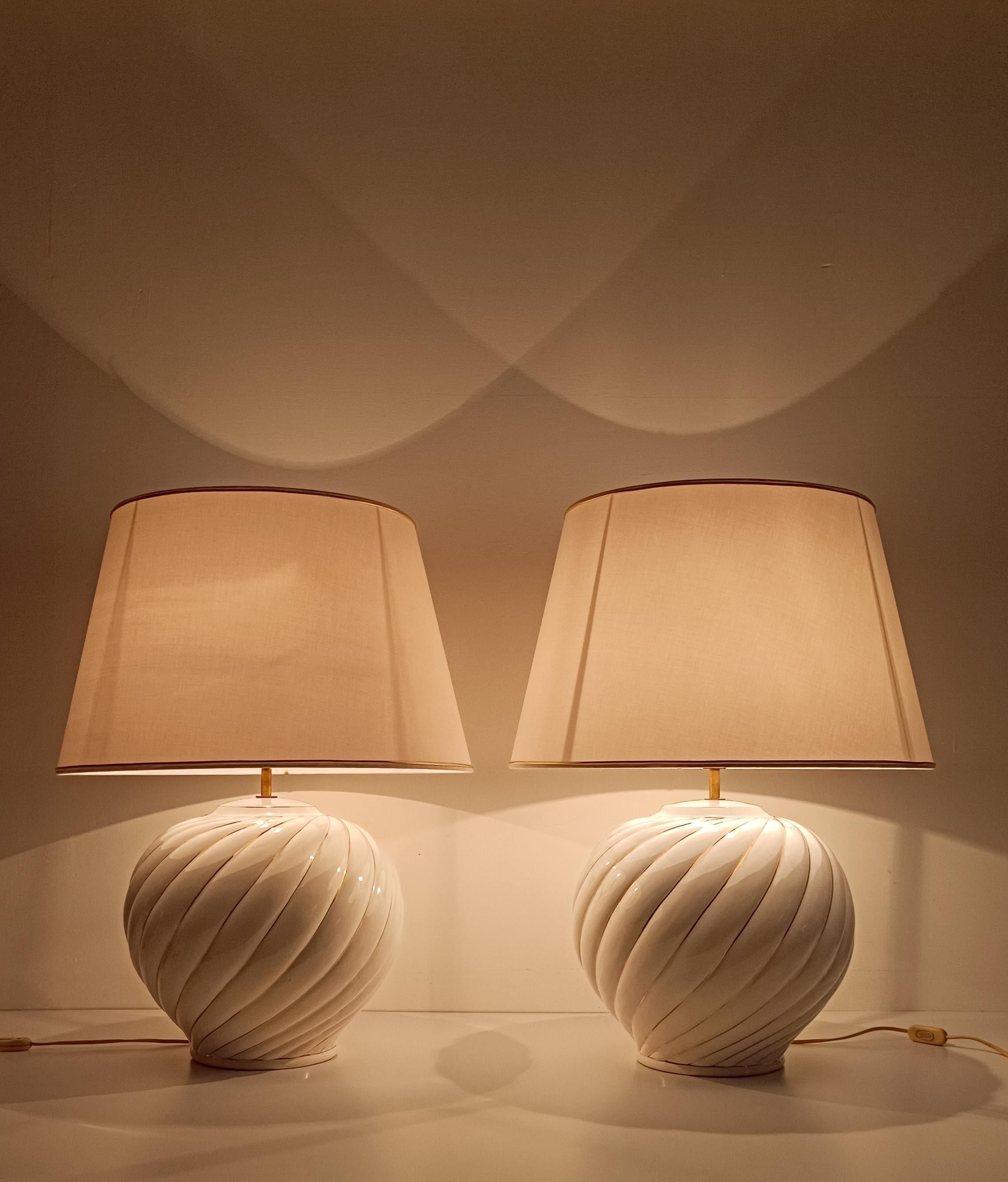 we offer for sale an amazing set of 2 twin lamps designed by Tommaso Barbi, as attested by the signature under the base.
This pair of giant lamps were made in Italy during the 70s in white glazed ribbed ceramic.
The precious and luxurious materials