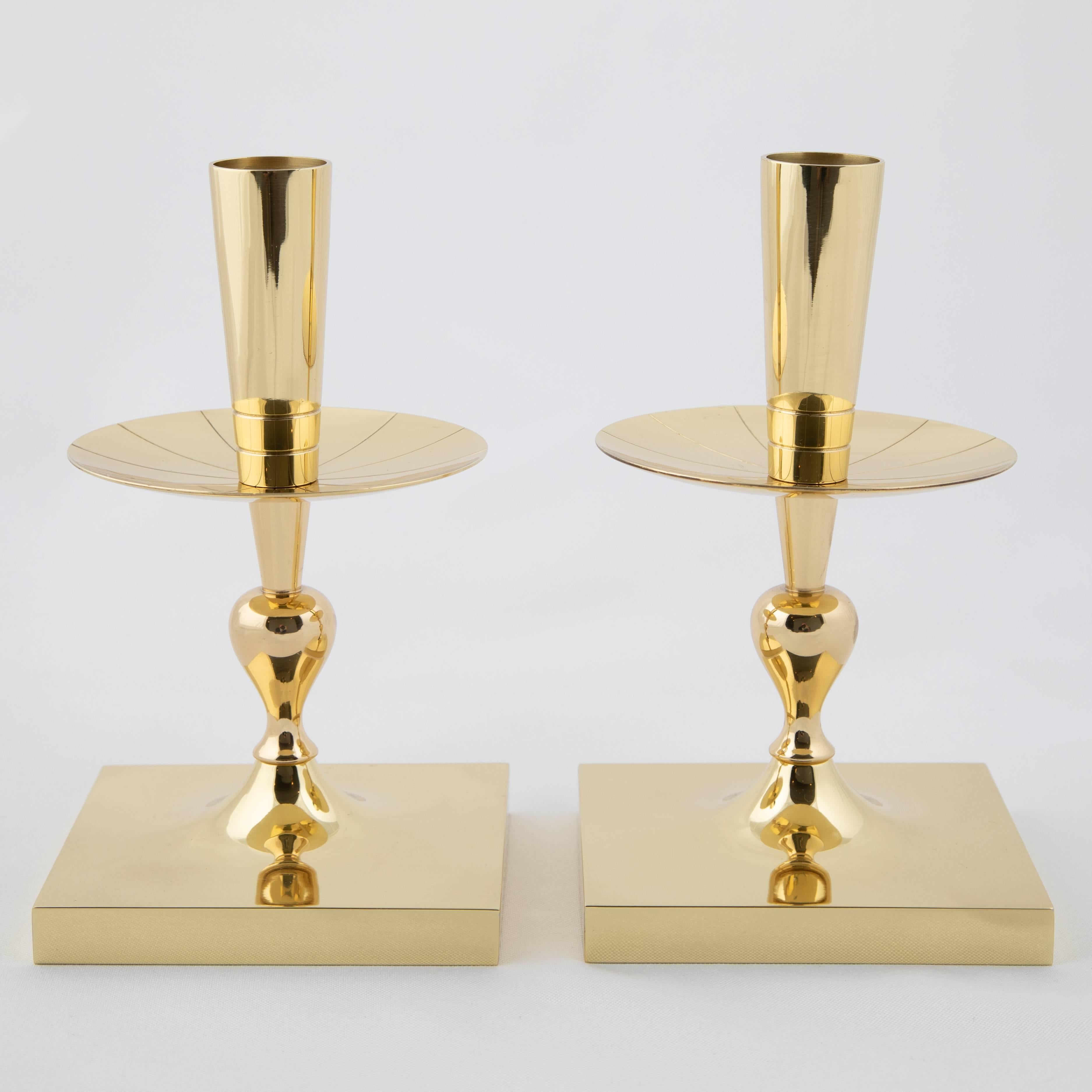 Compact pair of solid brass candleholders designed by Tommi Parzinger for Dorlyn Silversmiths. Square bases support round bobeches that feature Parzinger's signature radial incisions. Dorlyn Silversmiths stamp on underside of both.



