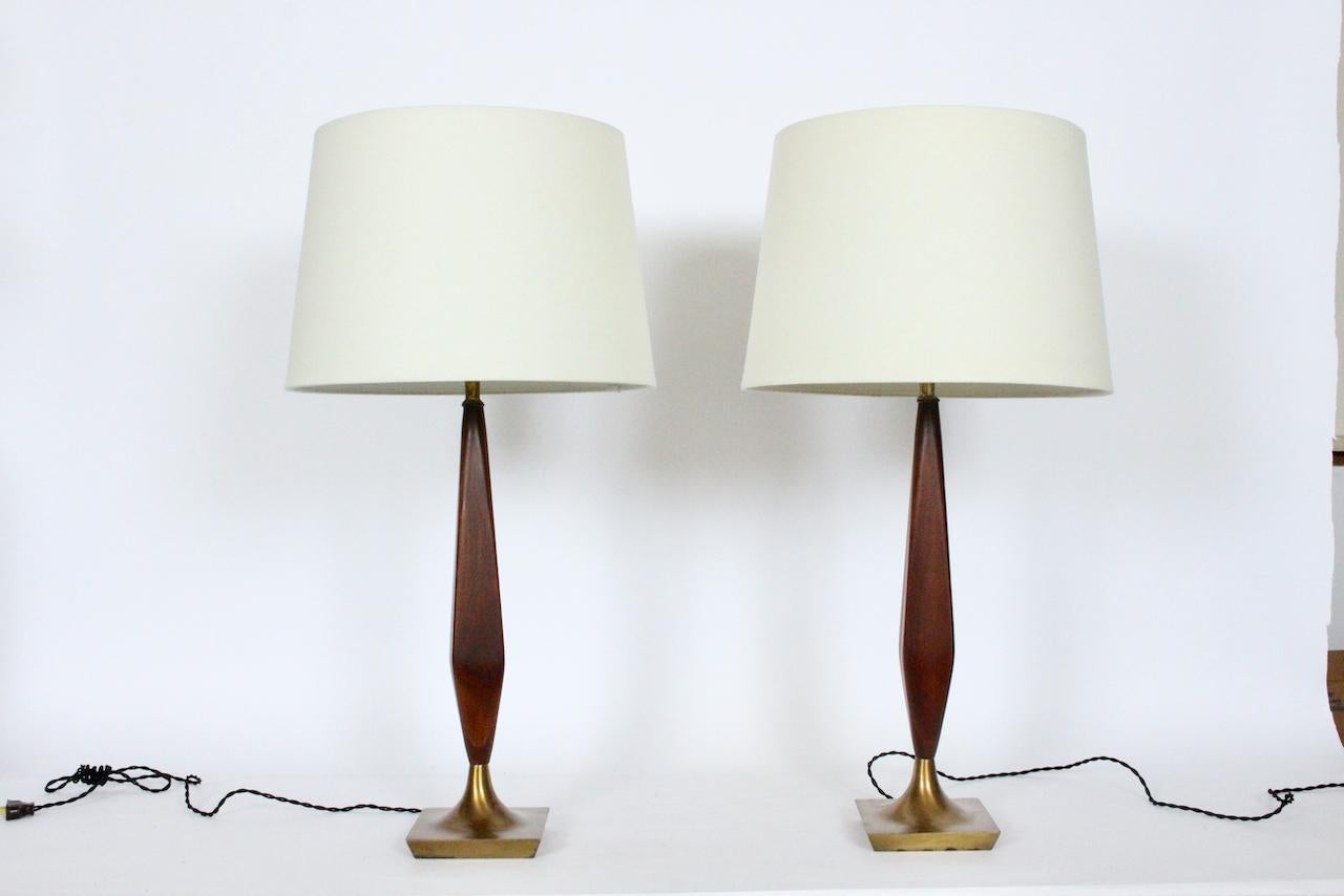 Pair of Tony Paul Style four sided black walnut and brass table lamps. Featuring a smooth rectilinear stem design in finished black walnut atop flared antique brass toned (5.5) square coaster bases. Small footprint. 22.5H to top of socket. 19H to