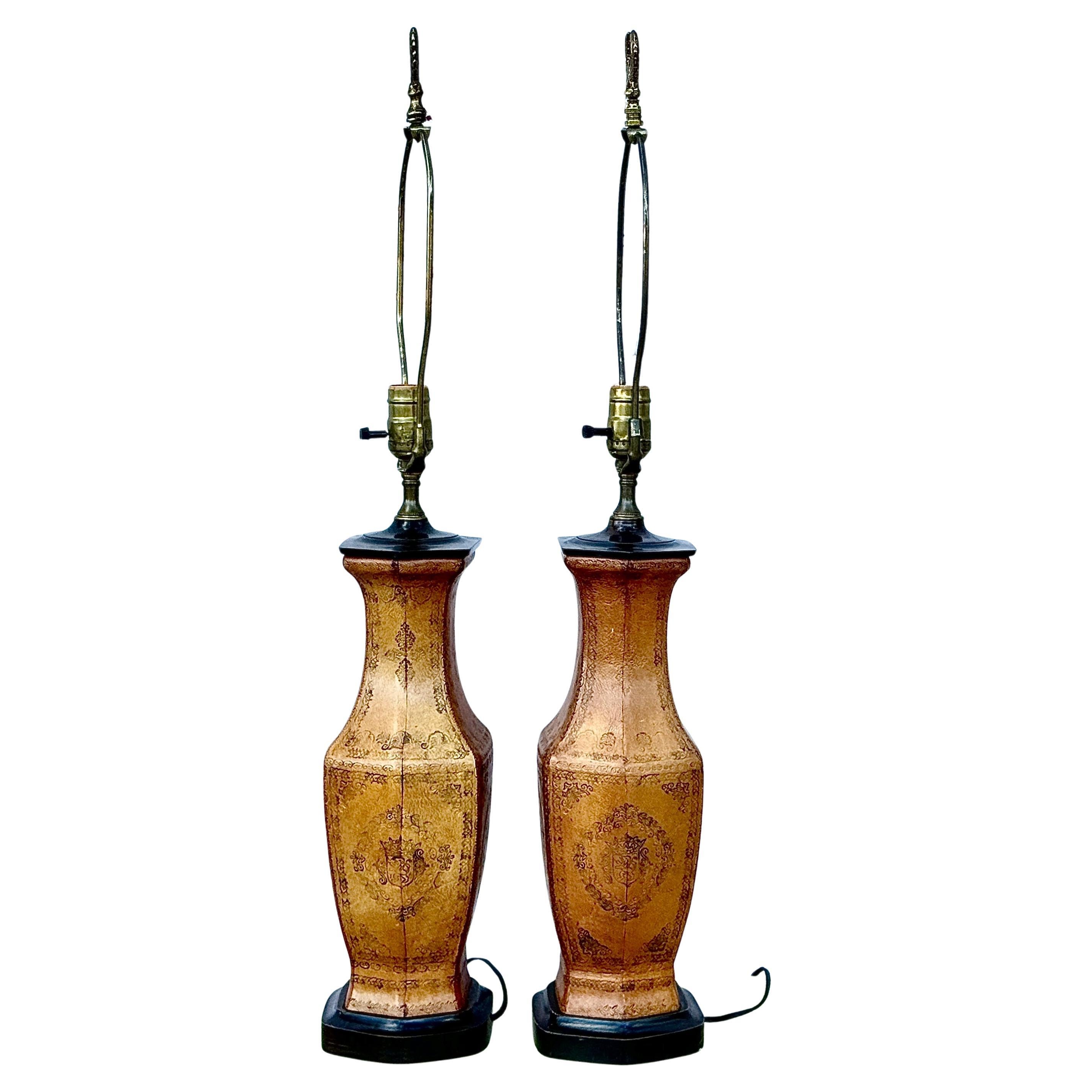 Mid-20th Century Tooled Leather Table Lamps with Coat Of Arms motif etched into leather. Lamps feature a classic old world aesthetic combining camel colored leatherwork with functional lighting. The center lion in the coat of arms symbolizes