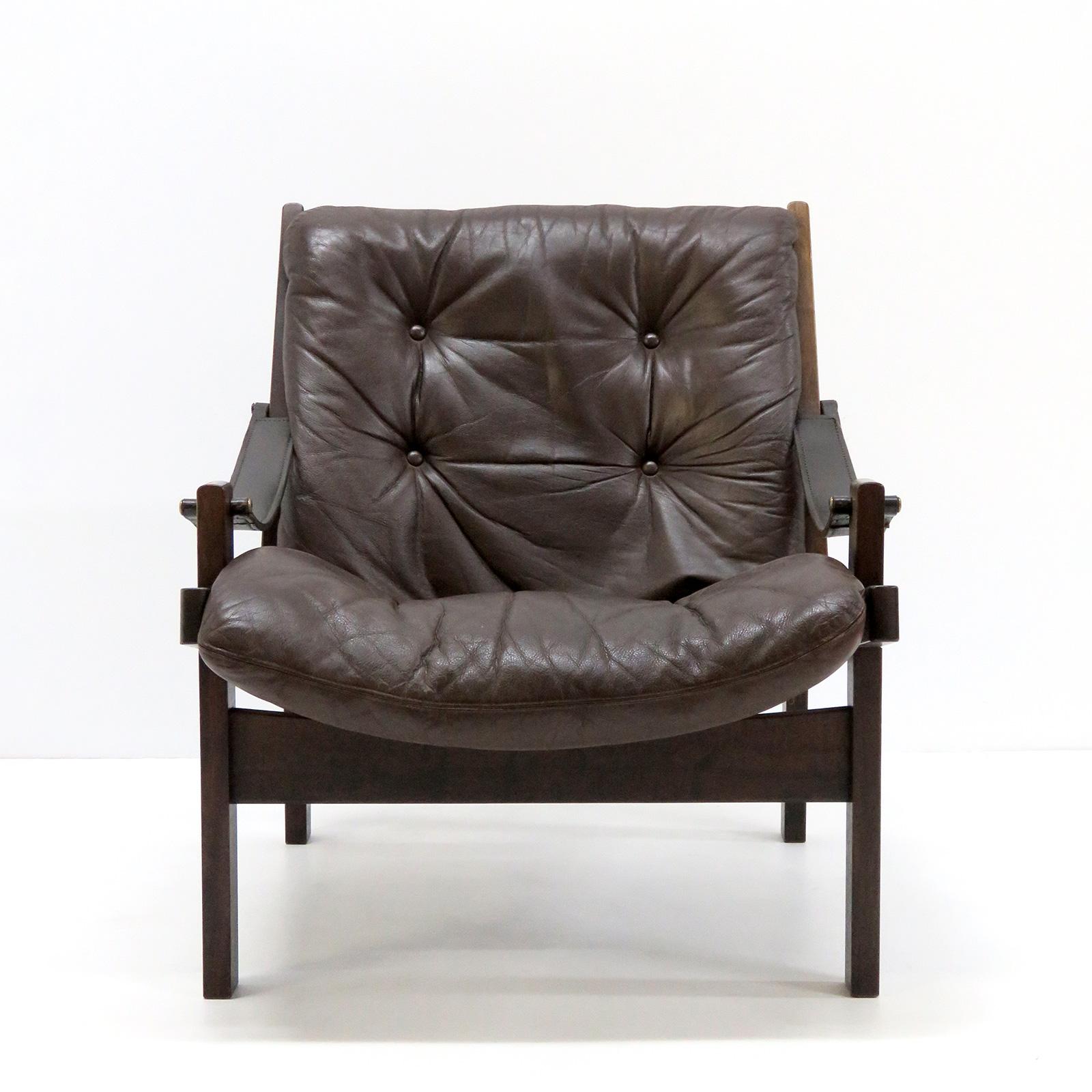 Stunning easy chairs with chocolate brown leather and stained hardwood frame designed in the 1960s by Torbjørn Afdal for Bruksbo, Norway. Sling armrests in leather, canvas weave holding the tufted leather cushion in place. Great vintage condition.