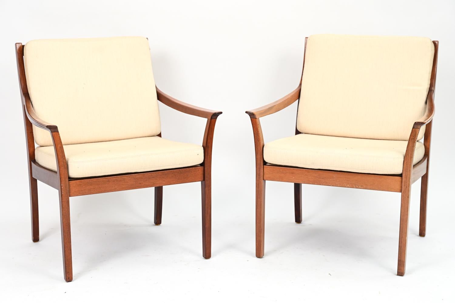 A rare, elegant pair of Danish mid-century lounge chairs with unusual slatted backs, gracefully curving armrests, and cream wool cushions by Torbjorn Afdal, whose highly sought designs were bought by US first lady Jacqueline Kennedy and by the