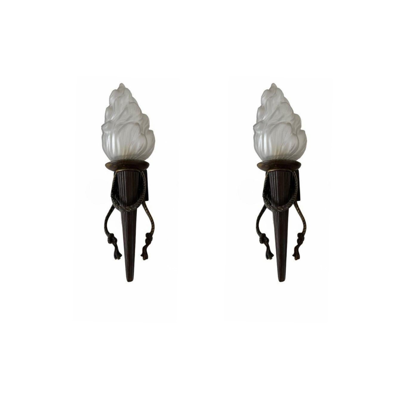 Very nice pair of sconces manufactured in heavy bronze and with pressed glass lamp shades depicting Torches.
These hold bayonet bulbs but can be changed for more modern ones easily.
There is some rubbing to the back of one scone which shows the