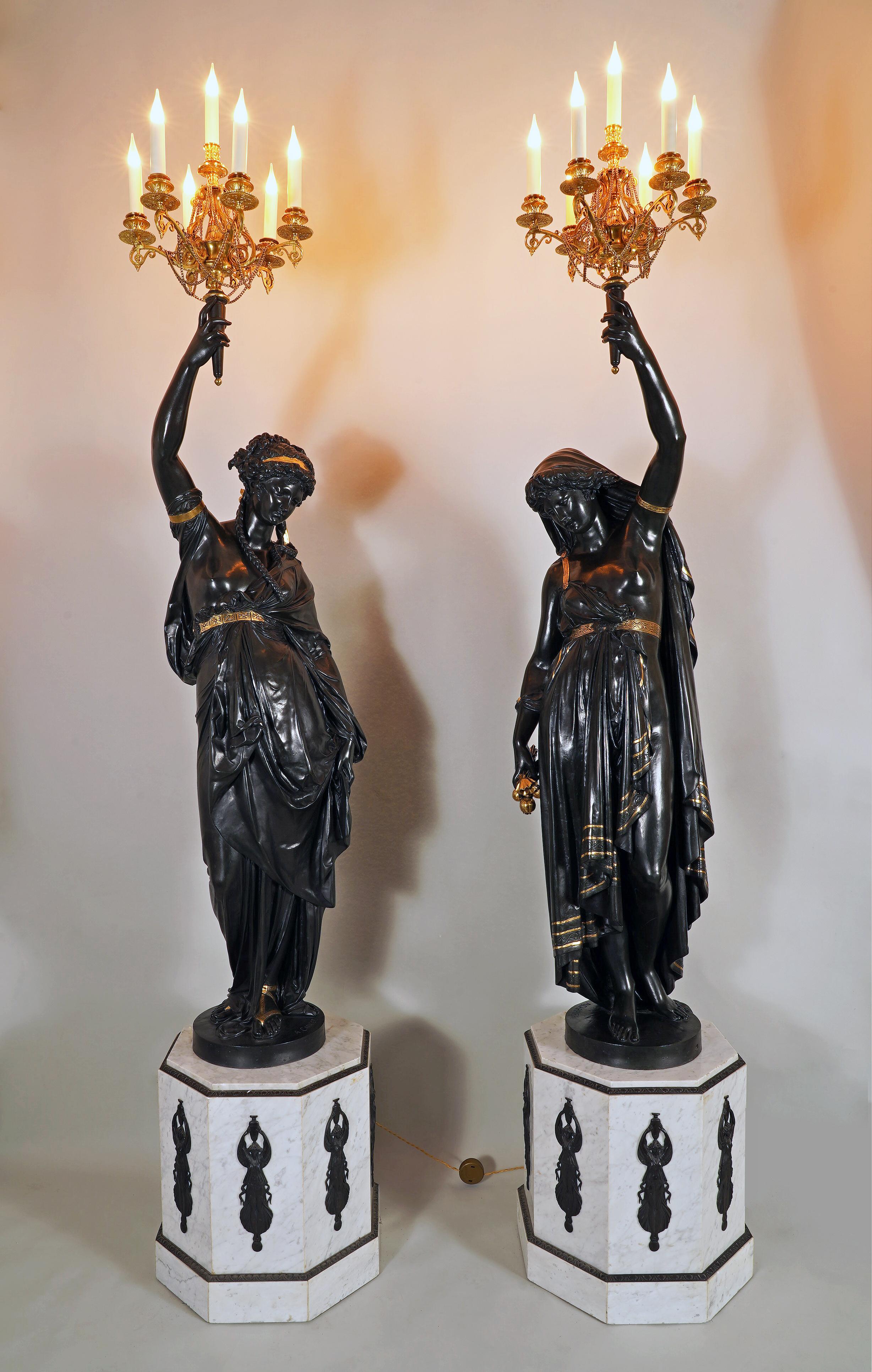 Hauteur totale : 257 cm (101,2 in.) ; Hauteur de la base : 52 cm (20,5 in.) ; Largeur de la base : 48×48 cm (18,9×18,9 in.)

Exceptionnelle paire de torchères féminines, en bronze patiné foncé avec des reflets dorés. Chacune d'entre elles est