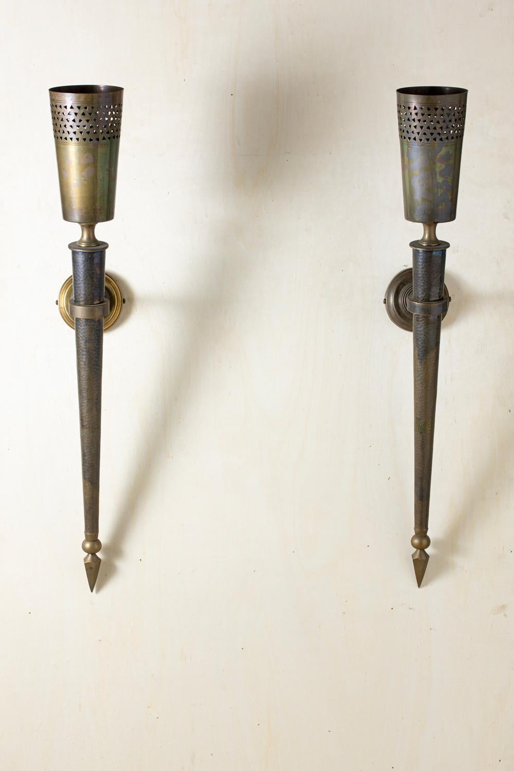 Oriental style torch sconces, in hammered and perforated brass, 1950s.

Four wall lights available (two pairs).

Measures: Height posed 37.4 in
Torch height 41.4 in
Depth (from wall to top edge) 15.8 in
Diameter 5.9 in.