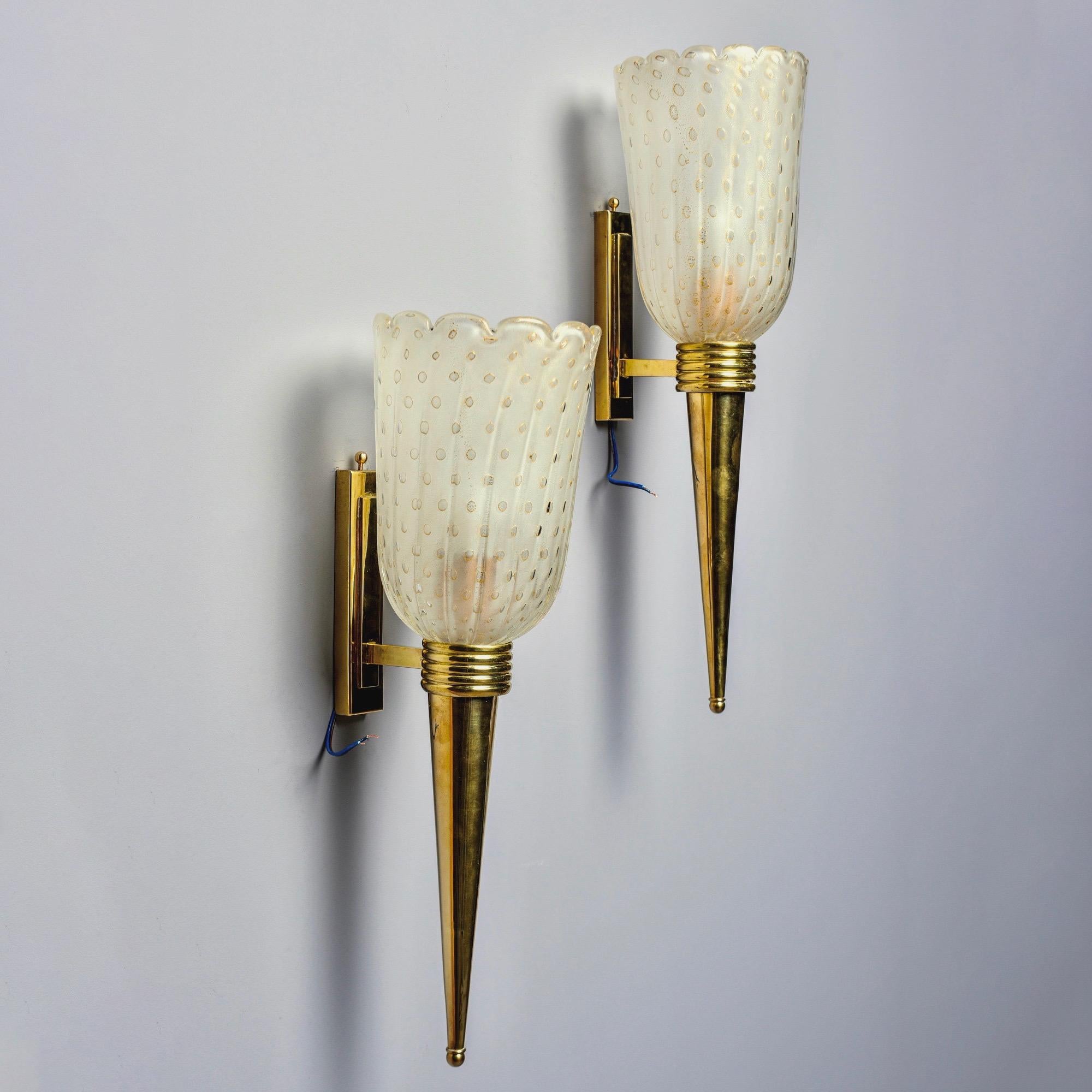 Made in Italy, this pair of torchiere style sconces feature a polished brass base and hand blown Murano glass globes with gold inclusions. Each sconce has one candelabra sized socket. Wired for US electrical standards. Sold and priced as a pair.