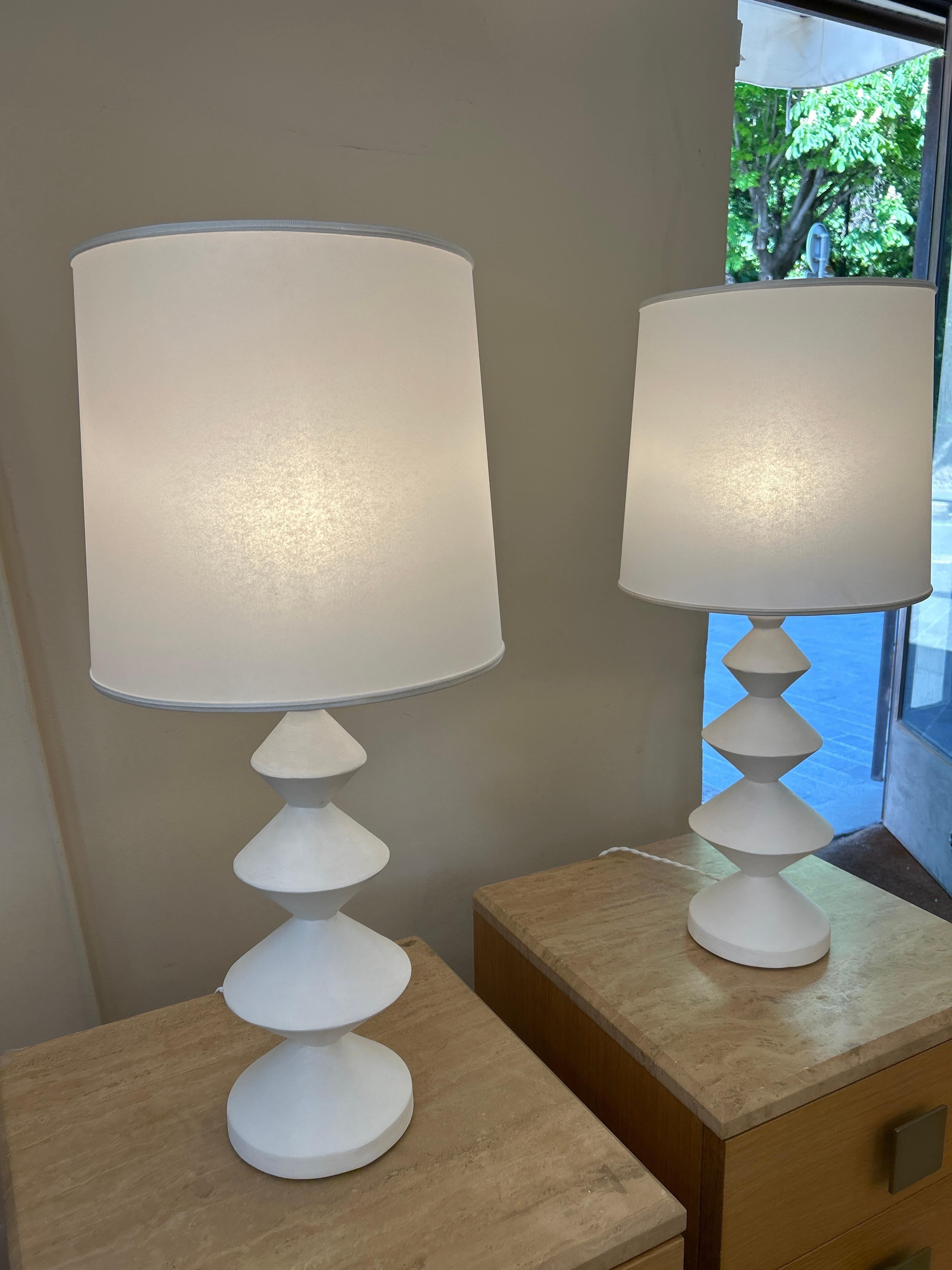 Ces lampes présentent un design moderne et sculptural, avec une base en forme de totem composée de disques empilés aux contours géométriques et effilés.
Ils présentent une esthétique contemporaine et minimaliste, presque inspirée du design