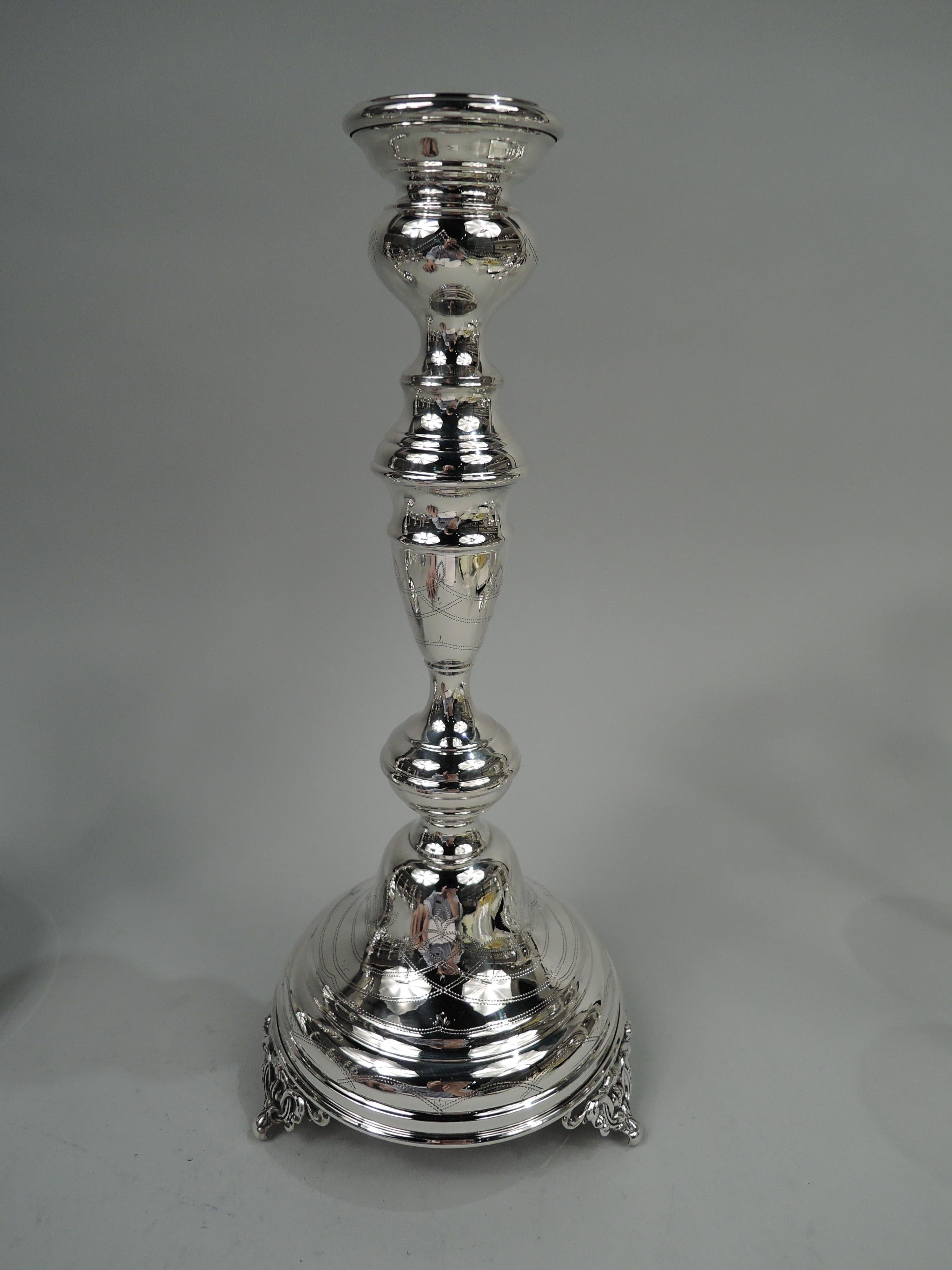 Pair of Old Country sterling silver candlesticks. Made by Elgin Silversmith Co., Inc. in New York, ca 1950. Each: Bellied socket on baluster shaft; domed foot with three embossed scroll supports. Naif-style pointille ornament. Marked “ESCO /