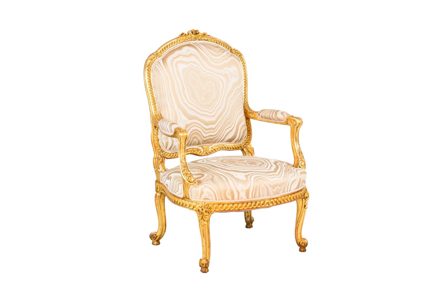Pair of Transition style armchairs in giltwood standing on four cabriole legs ending in scroll with a decor of acanthus leaves. Slightly bulged apron adorned with an interlacing frieze. Arm supports slightly behind the leg line adorned with acanthus