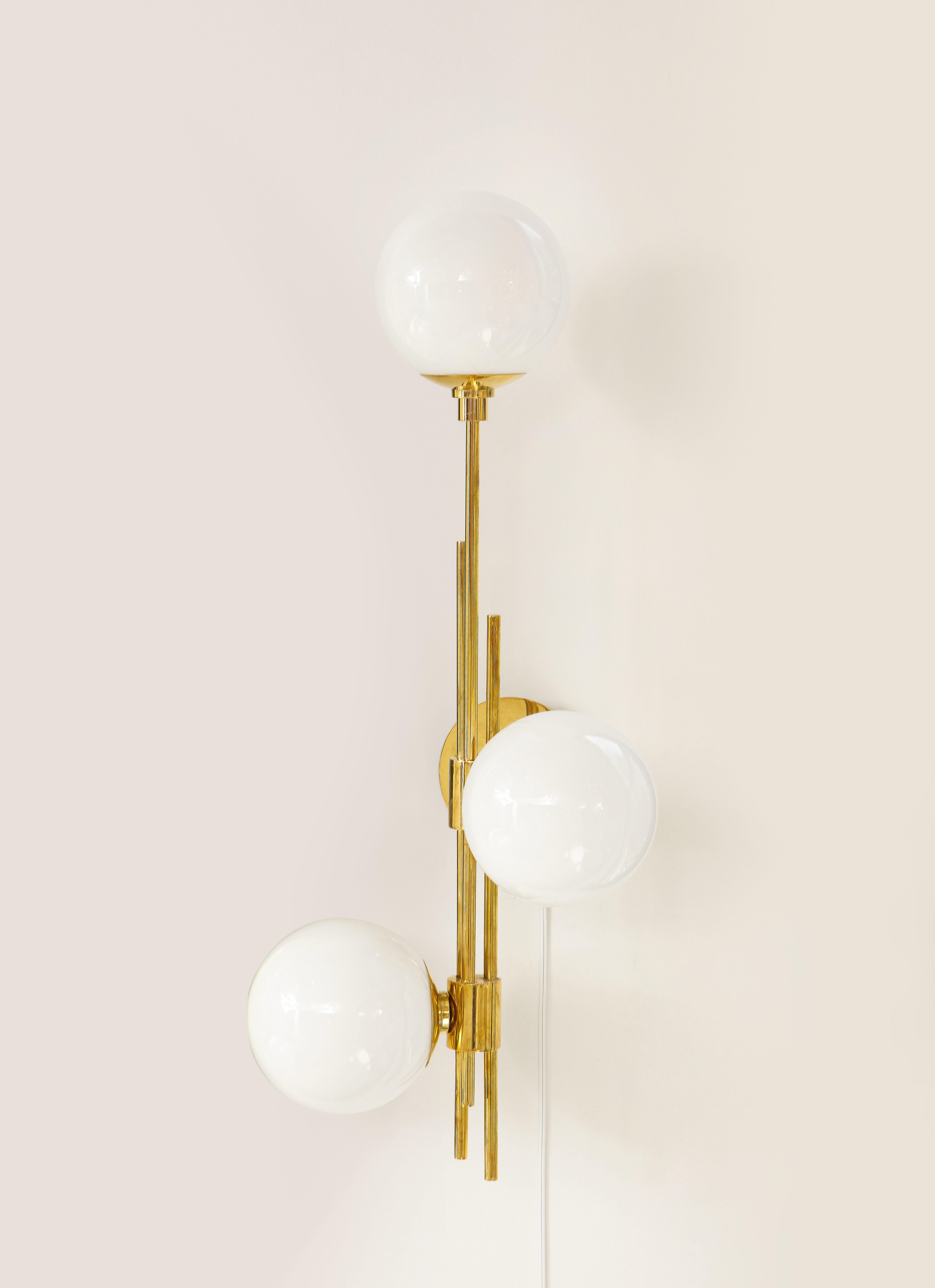 Pair of translucent white murano glass globes and brass sconces handcrafted in Italy, 2022. Clean lines describe this pair of linear sconces, consisting of three (3) translucent white glass globes at different heights attached to polished brass