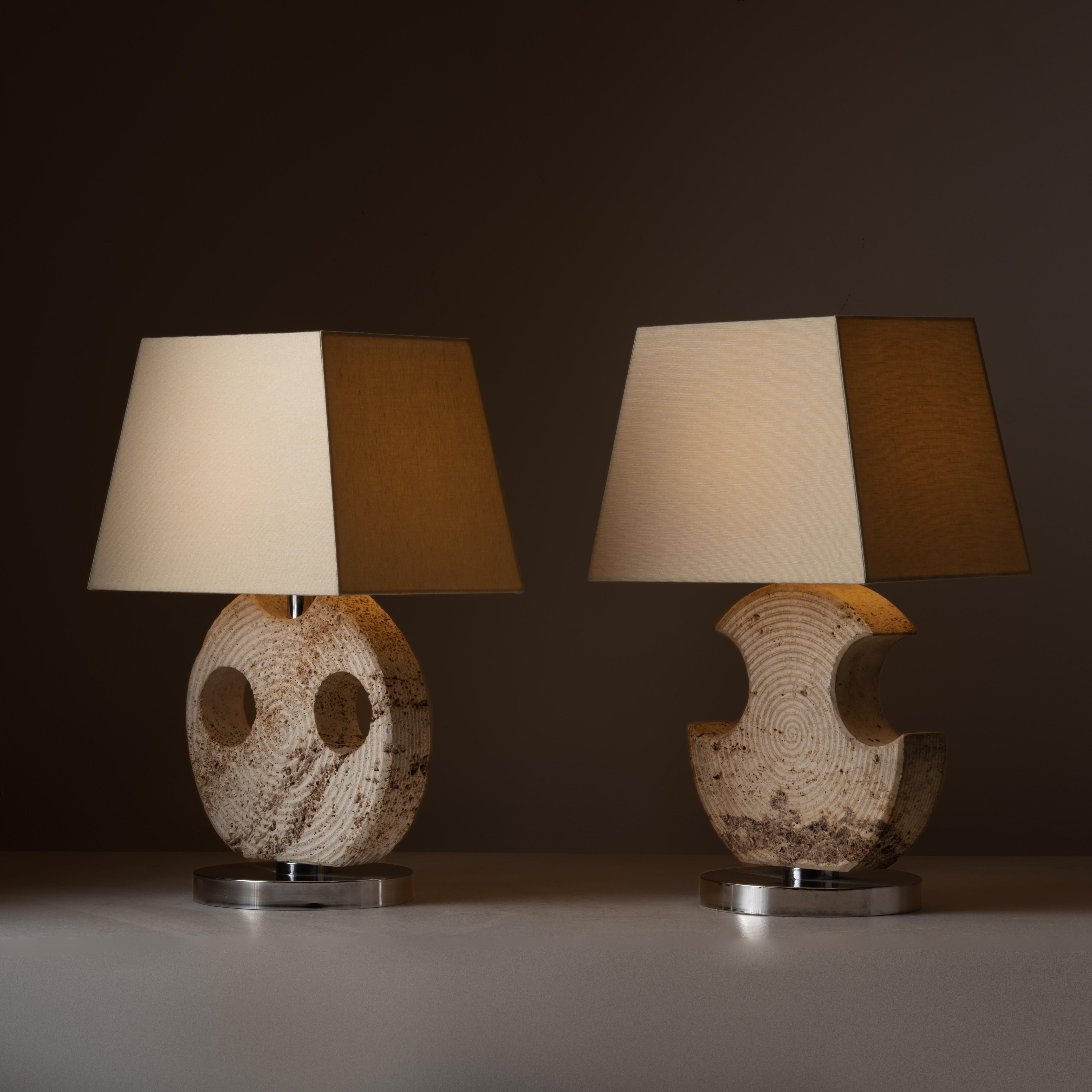 Pair of travertine table lamps by Studio CE. VA Milan. Designed and manufactured in Italy, circa 1970. Sculptural and carved travertine table lamps, with chrome finish circular bases and beige linen shades. Each lamp holds one E27 bulb socket. We