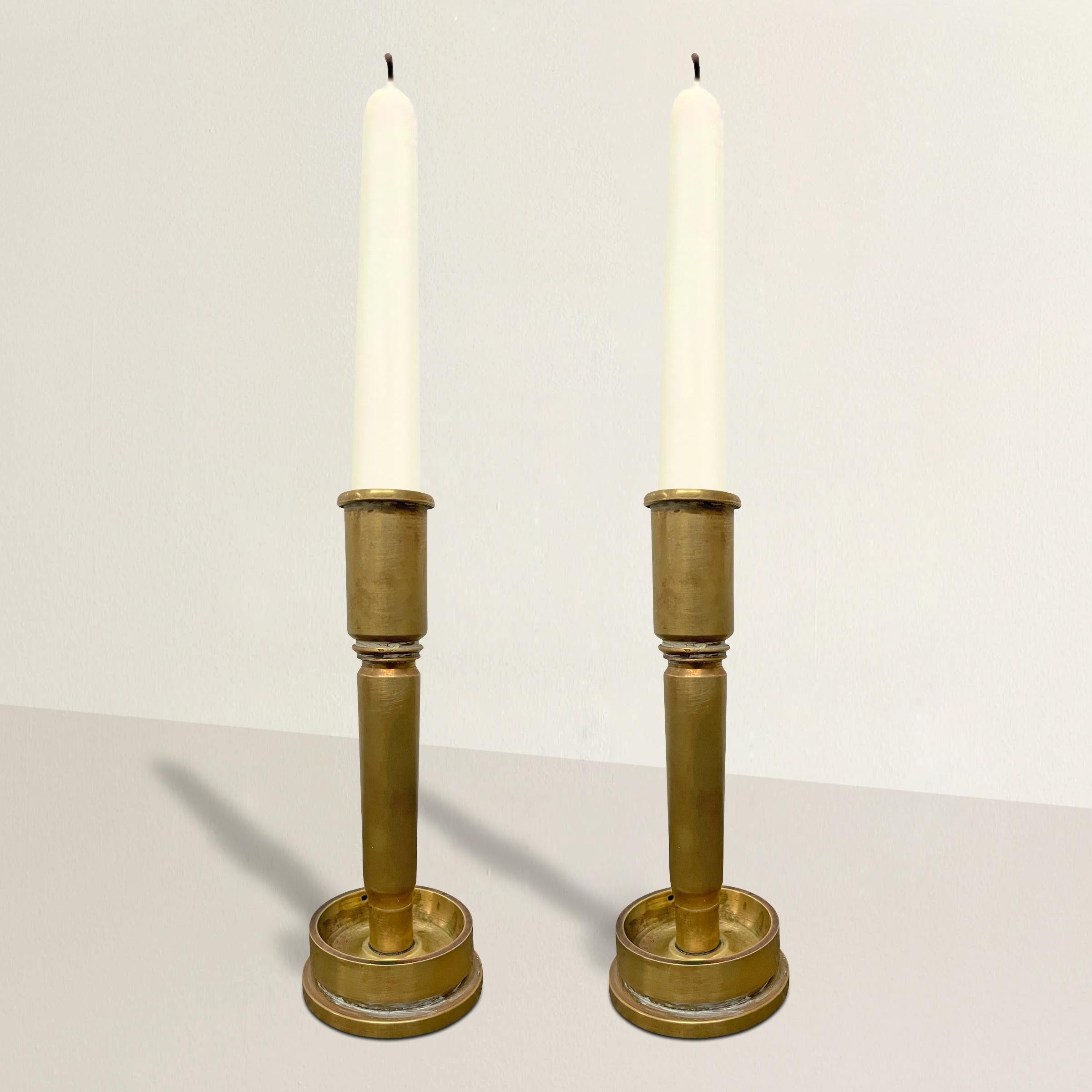 A wonderful and thought provoking pair of early 20th century American Trench Art candlesticks made from the spent brass casings of naval artillery shells.