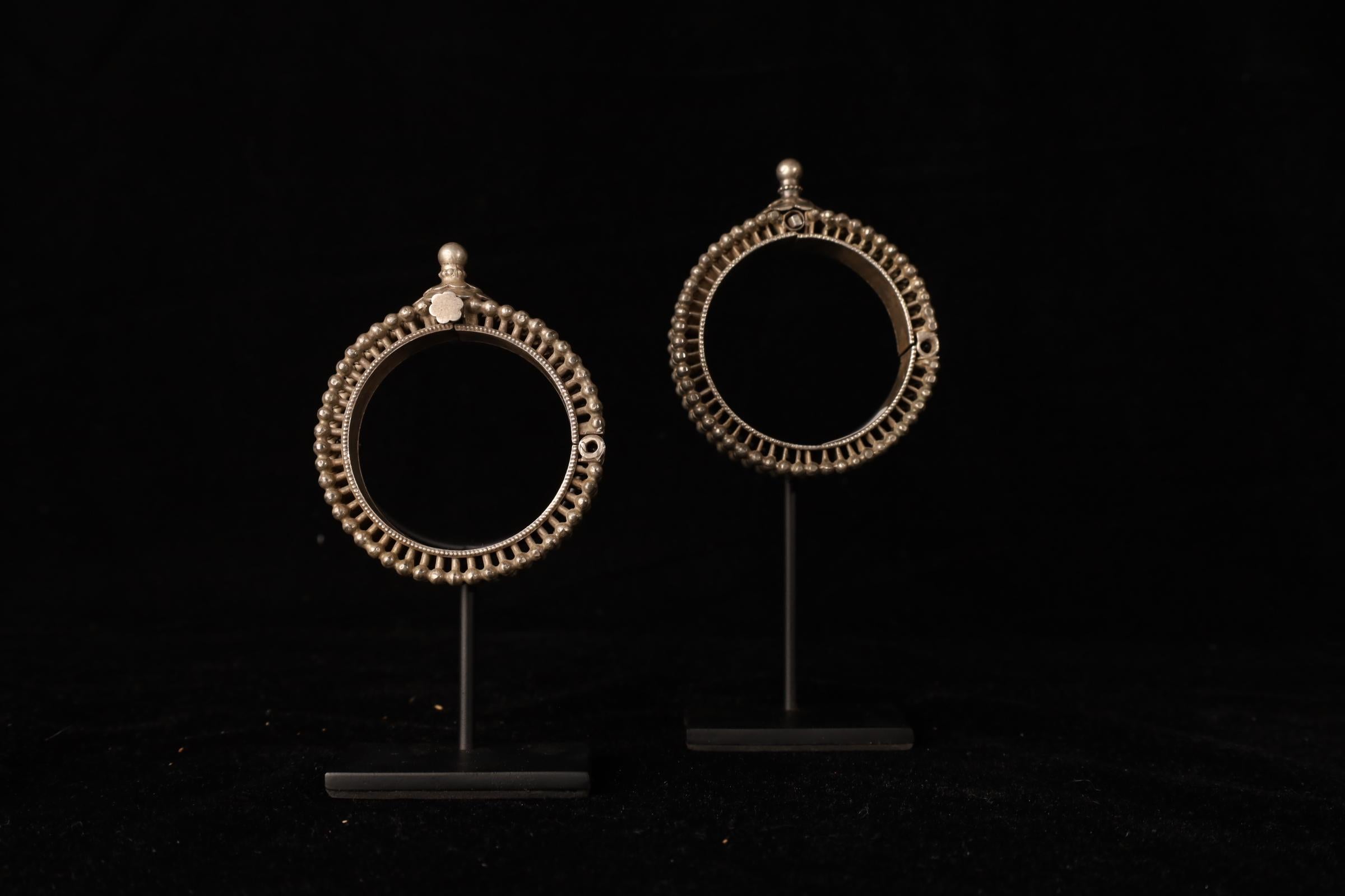 A striking pair of 19th-century tribal bracelets from India, crafted in solid silver and distinguished by their bold, architectural form. Each bracelet features a sculptural ring-shaped body with finely textured surface detailing, characteristic of