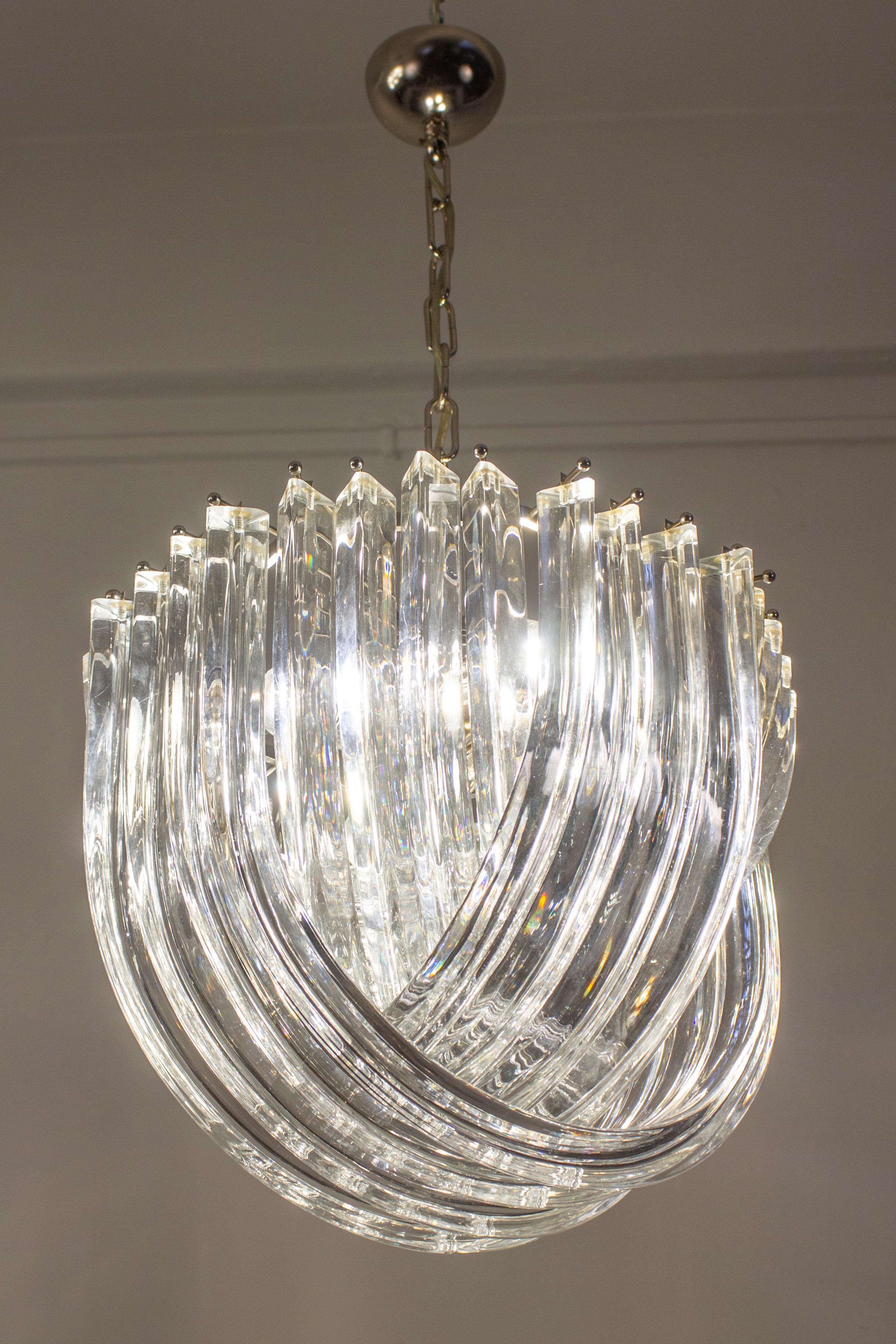 Amazing pair of glass chandelier or ceiling light with four layers of curving “triedri” glass prisms on a brass frame, designed by Carlo Nason for Venini, Italy.
A dynamic form, changing as you move around it, due to the overlapping levels of