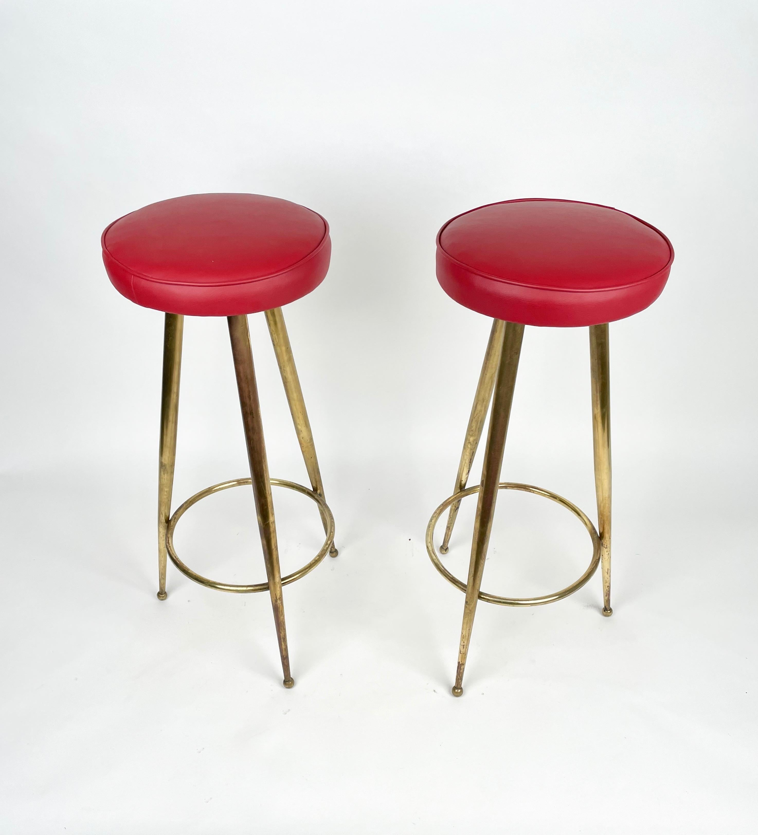 Magnificent pair of Mid-Century Modern bar stool in red vinyl and brass structure. This wonderful set was designed in Italy during the 1950s in the style of Gio Ponti.

These pair of bar stools were constructed with three solid brass tapered legs