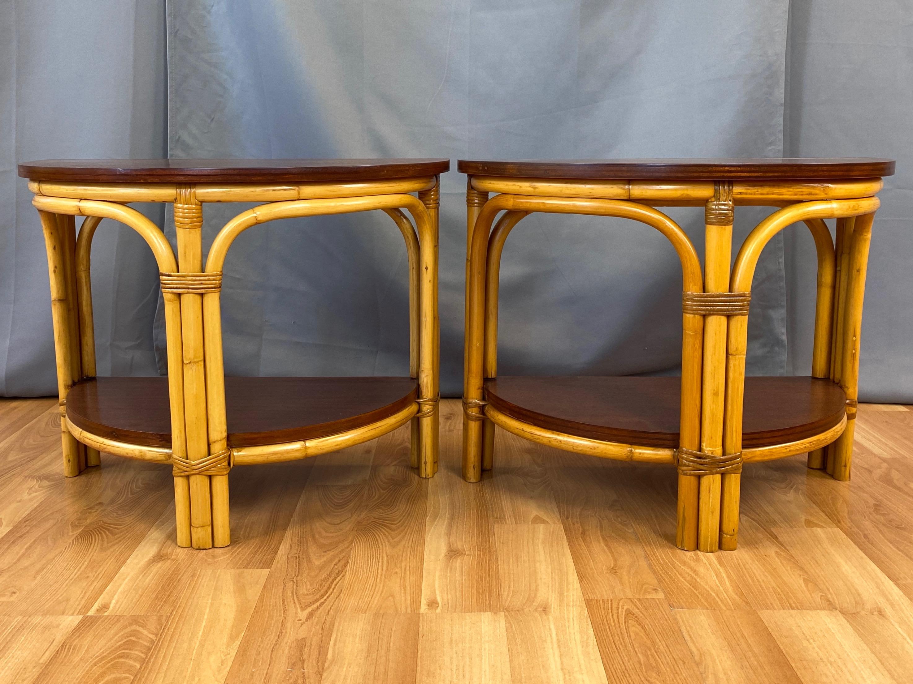 A pair of lovely mid-century rattan and mahogany two-level demilune side or end tables by Tropical Sun Co. of Pasadena, California.

Expertly-crafted bent rattan design features a trio of three-strand legs that elegantly branch off from and rejoin