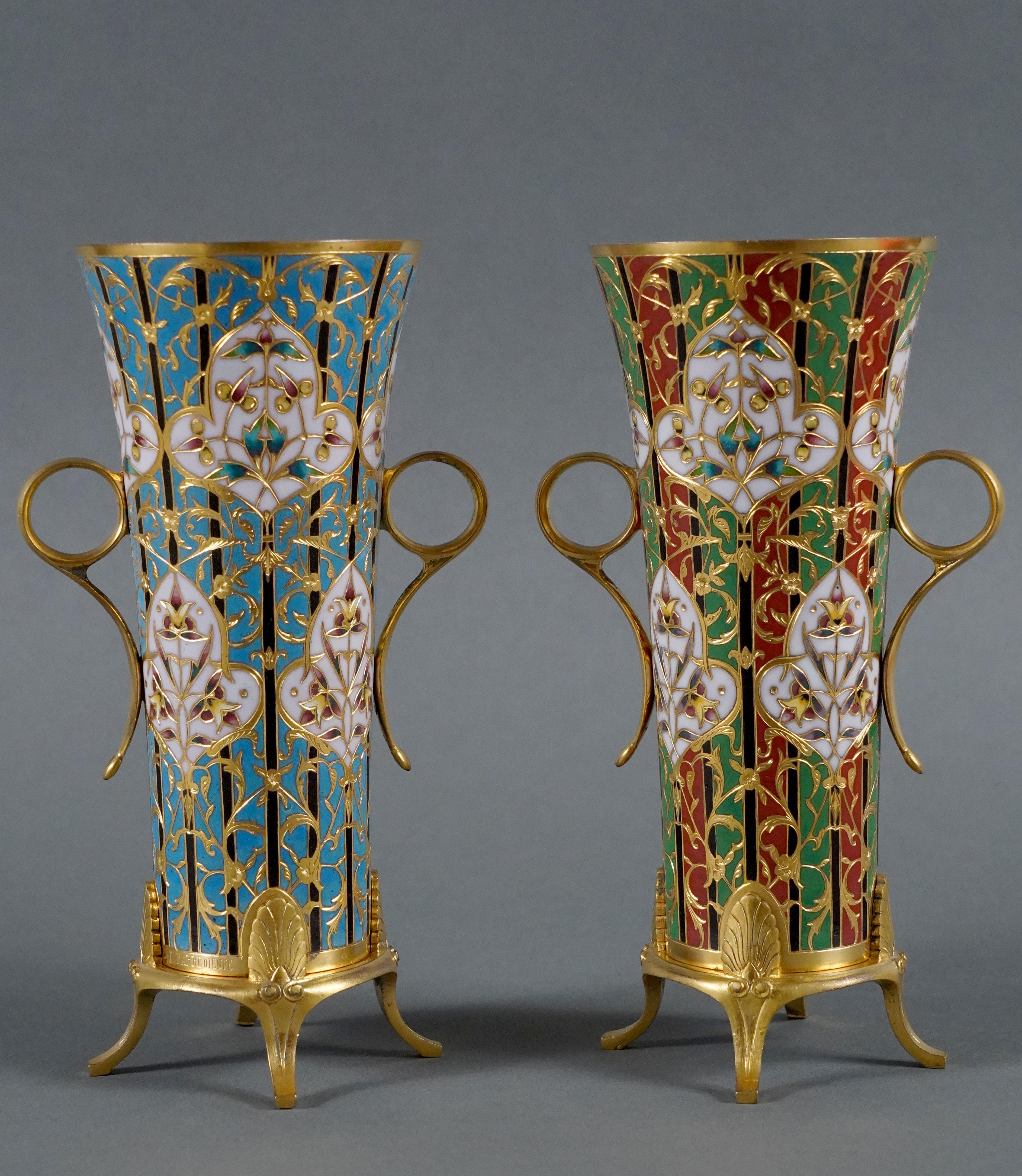 Signed F. Barbedienne

A pair of charming  trumpet-shaped vases in gilt bronze with a polychrome cloisonné enamel decoration, one blue and the other green and red. They feature two annular handles and stand on four feet surmounted by a stylized