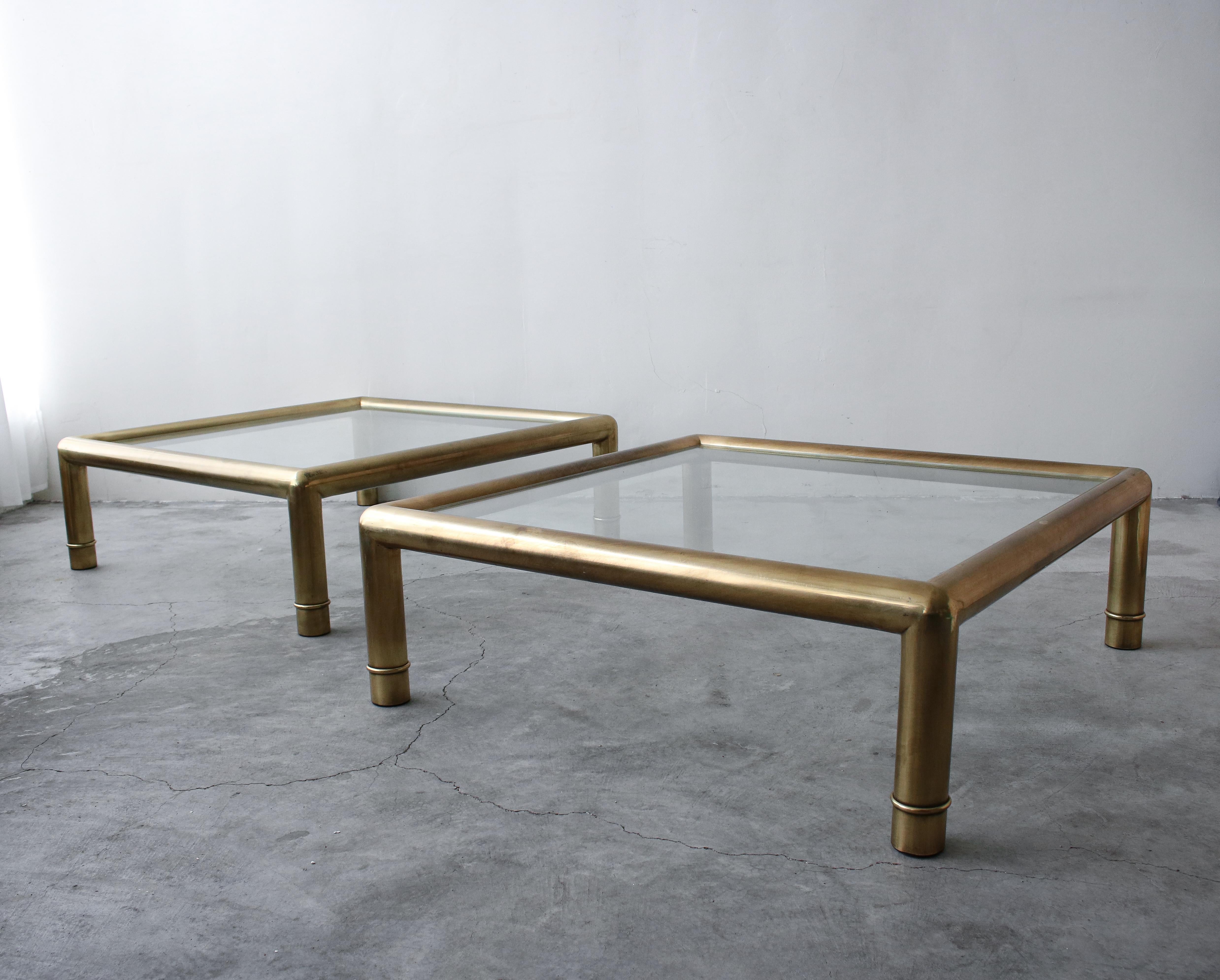 A beautiful pair of brass Mastercraft coffee tables. Large coffee tables are rare but even more rare in pairs. This gorgeous duo is beckoning for some great designer to unleash their potential. The chunky frames combined with the transparency of the