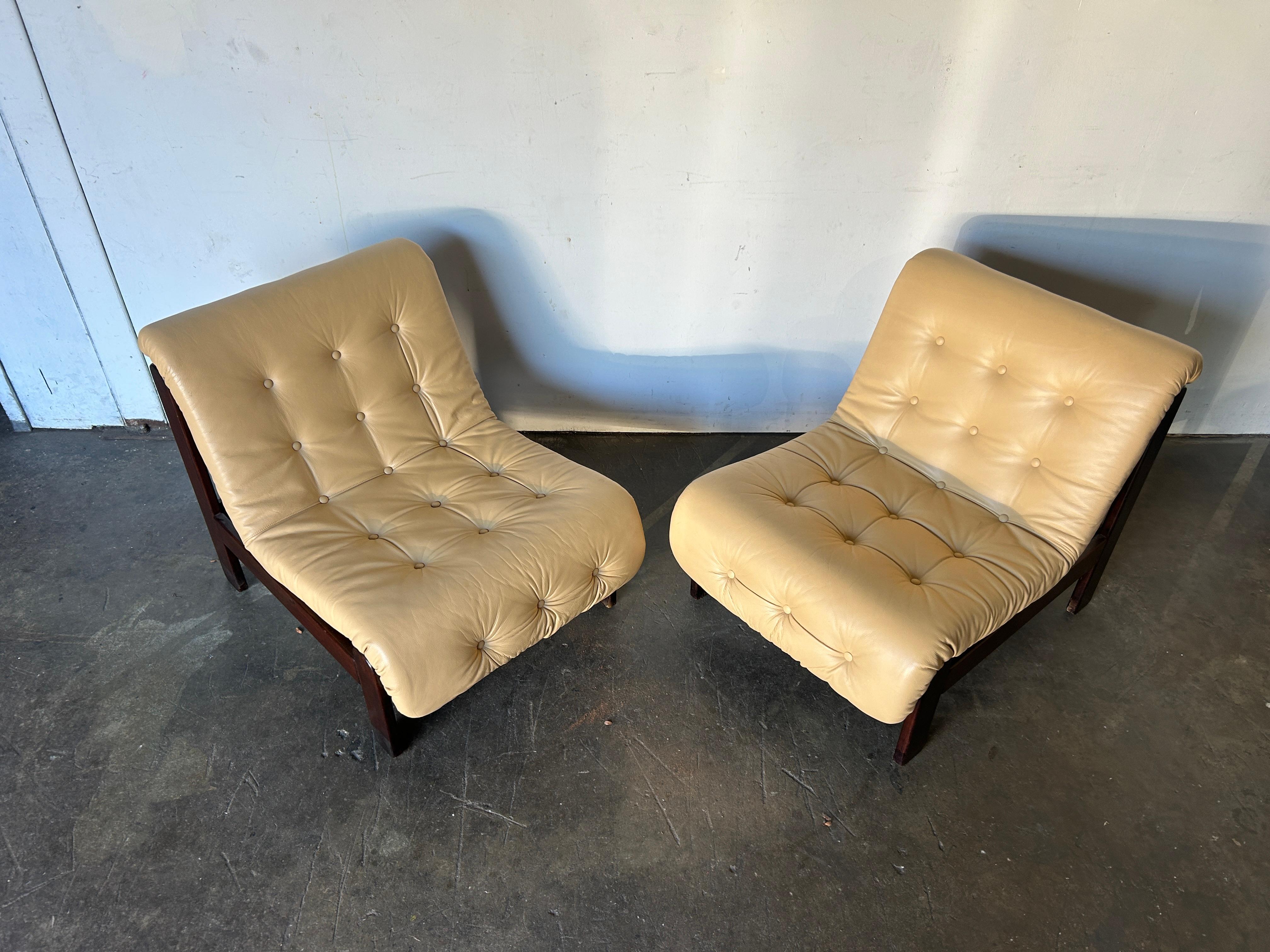 Paire de fauteuils de salon en cuir touffeté avec structure en bois. Superbe paire de chaises longues au design brésilien. Coussins en cuir souple tufté de couleur beige clair. Les coussins reposent sur des cadres en bois dur teinté foncé.