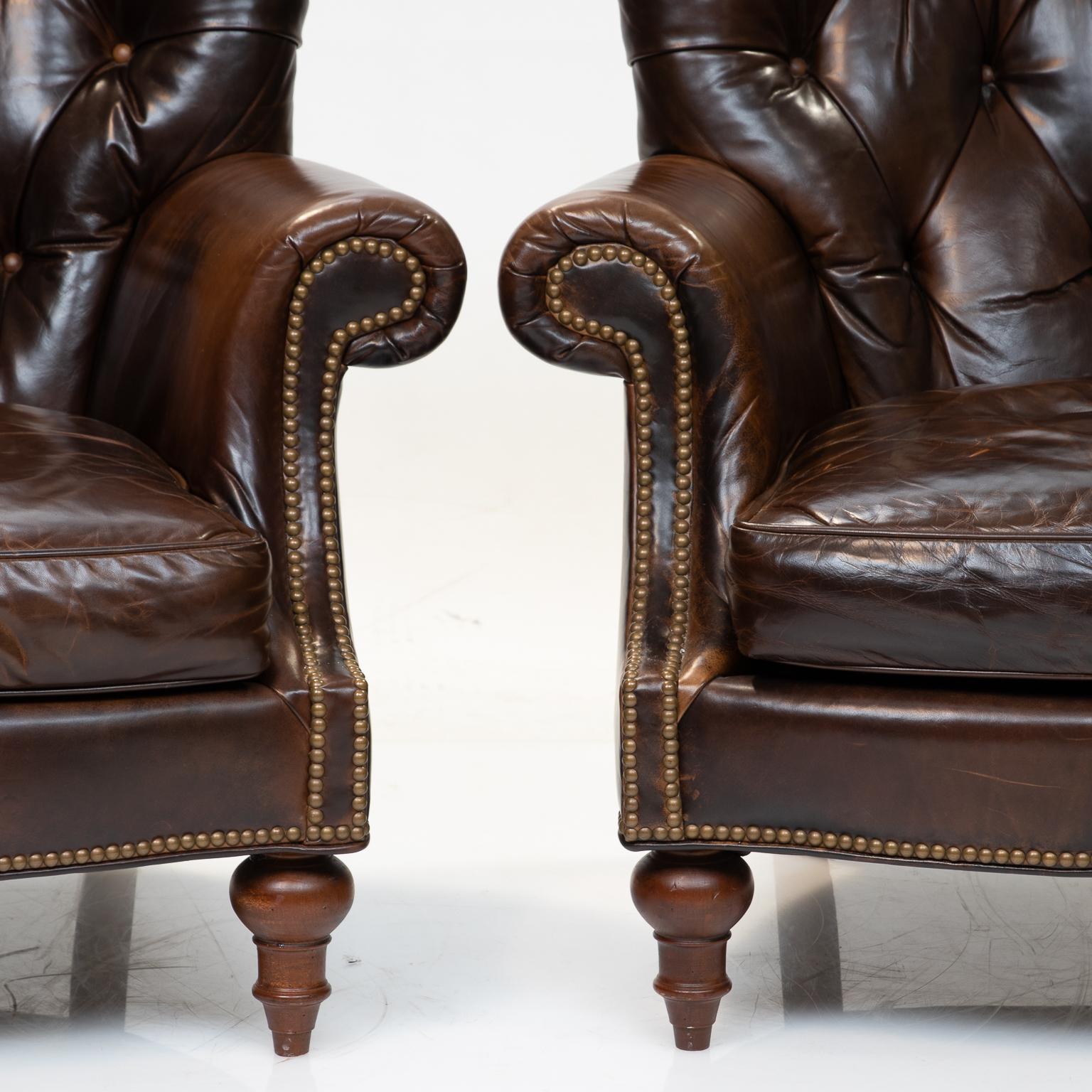 A fine pair of tufted barrel back and smooth cushion club chairs in a distressed belt grade leather. Exceptional brass nailheads. Resting on turned stout legs. These have been slightly used but only gives them a little more character. This leather