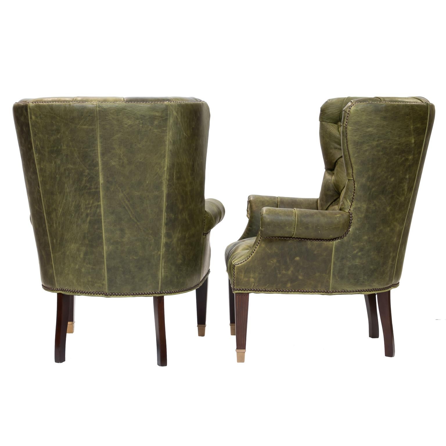A superb pair of leather tufted wing chairs. Resting on mahogany legs with brass caps.