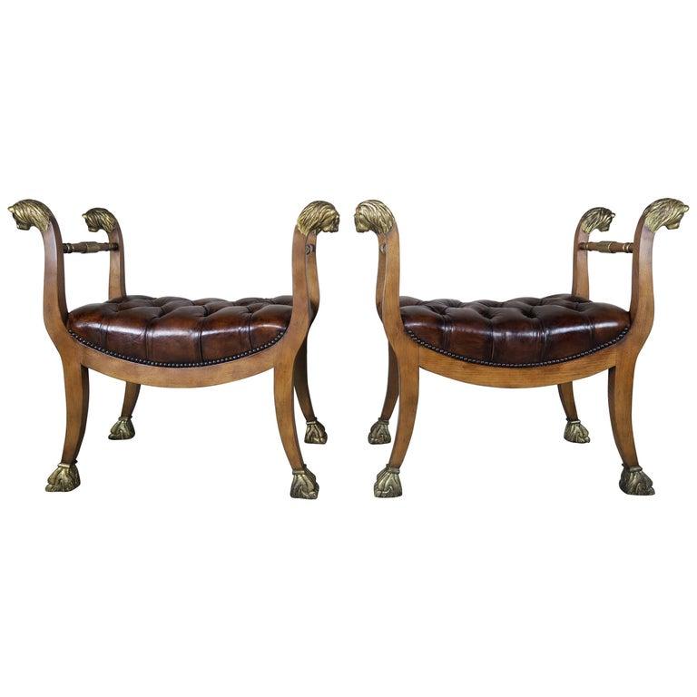 Pair of Baker Directoire style gilded 22-karat gold leaf lion head wood benches with tufted leather upholstery and nailhead trim detail.