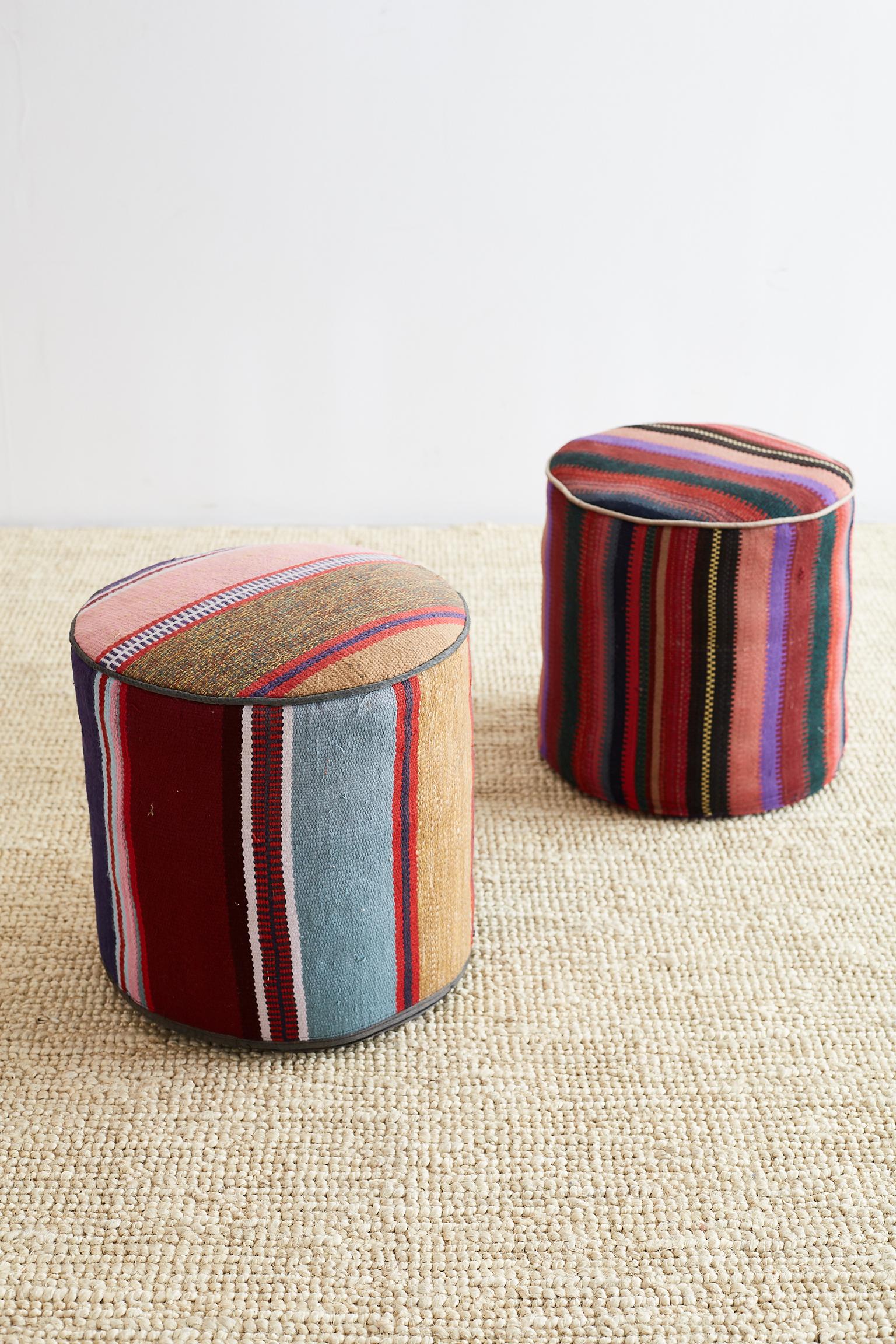 Colorful pair of Turkish Kilim striped pouf ottoman or hassocks. The stripe patterns feature geometric designs and the poufs have a round form.

Offered by Erin Lane Estate, Oakland, CA.