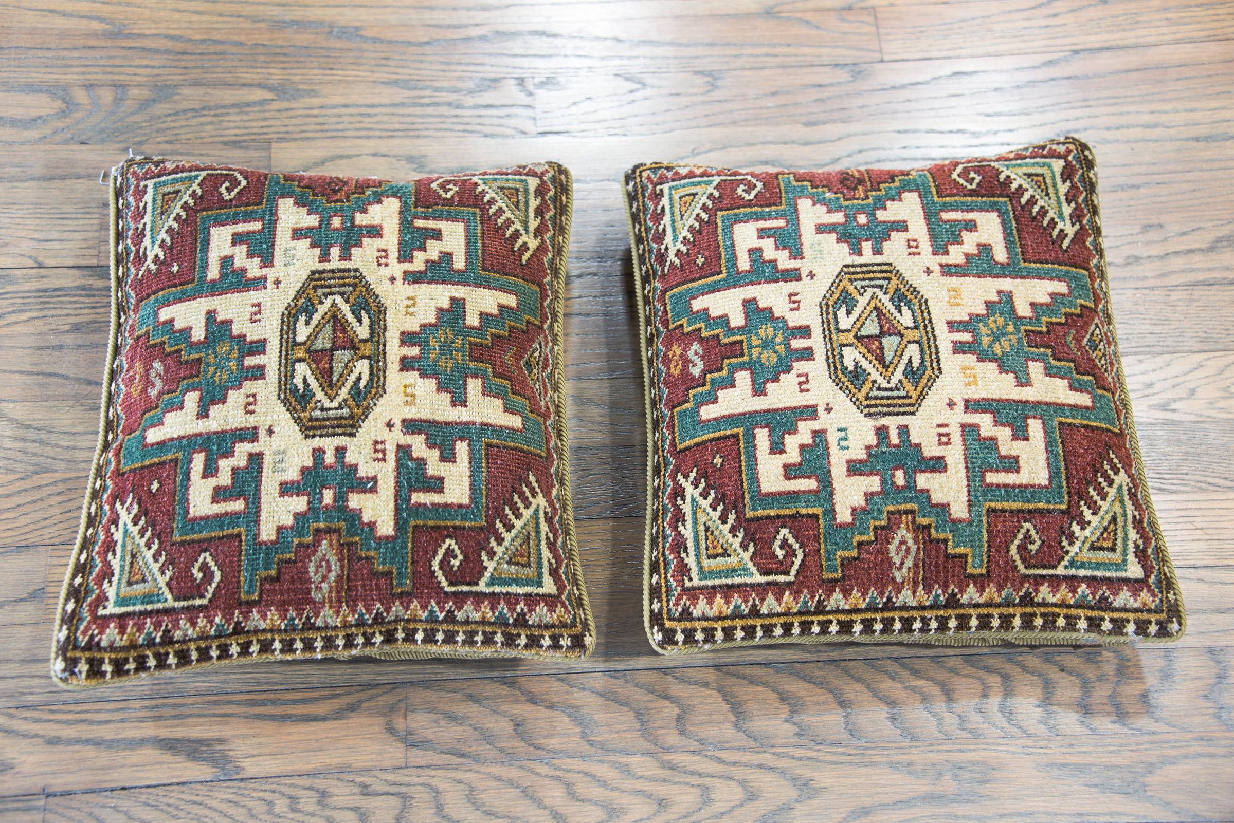 A pair of pillows made from a vintage Turkish rug, each with two large stylized floral medallions and simple geometric patterned borders.