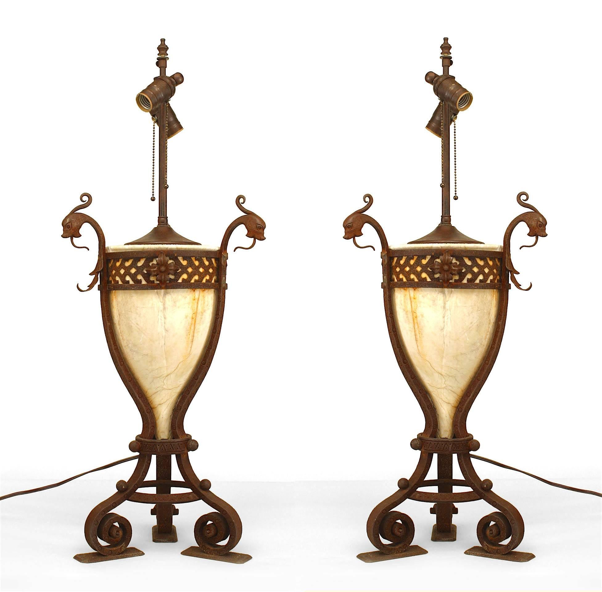 Pair of Italian Renaissance style (19/20th Century) alabaster vase form lamps within a wrought iron 3 section frame with mythological finial heads and scroll feet (PRICED AS Pair).
