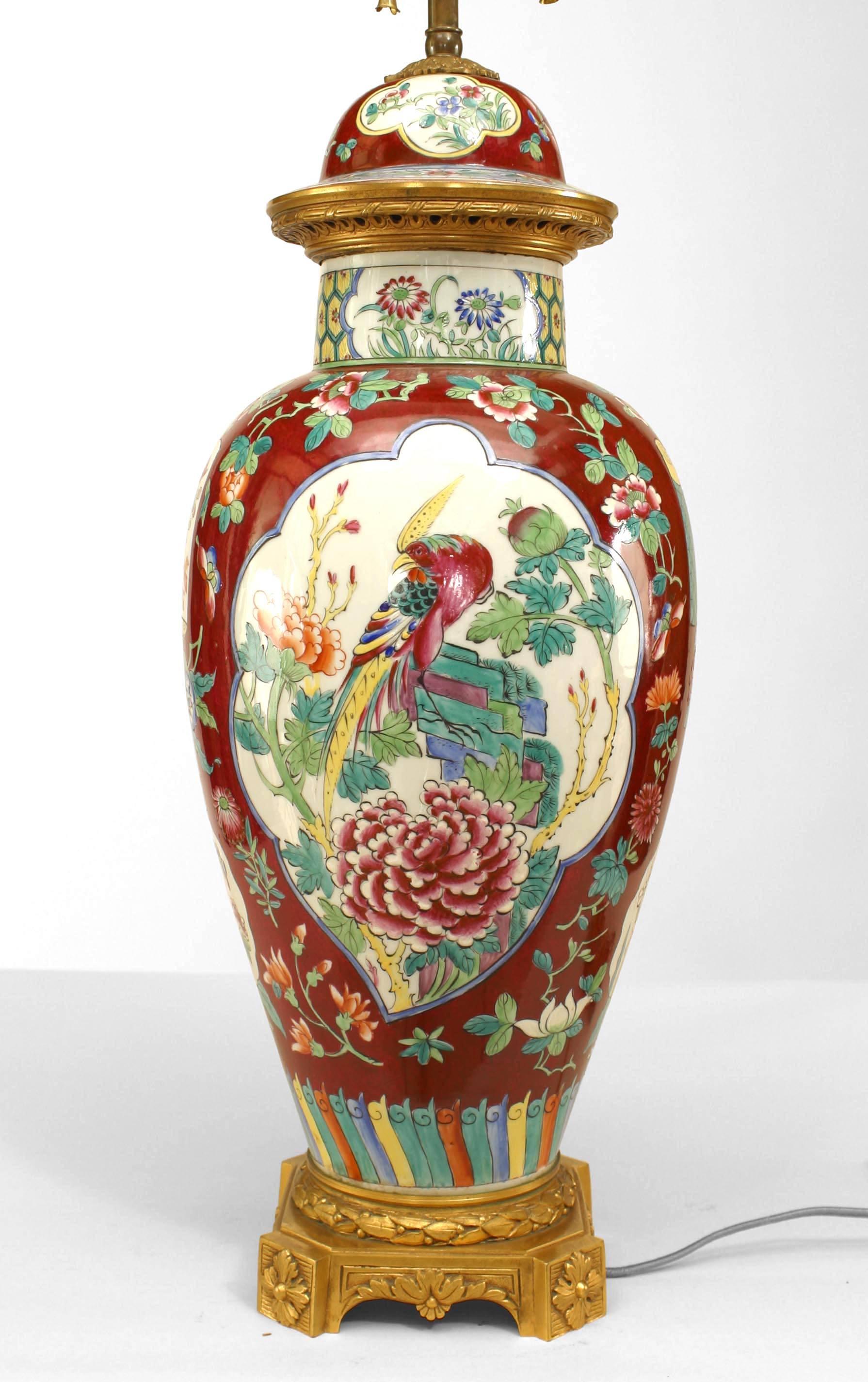 Paire de lampes asiatiques chinoises (19e-20e siècle) en forme d'urne en porcelaine oxblood avec couvercle présentant des détails d'oiseaux et de feuillages et montées sur une base en bronze (PRIX PAR PAIRE).
