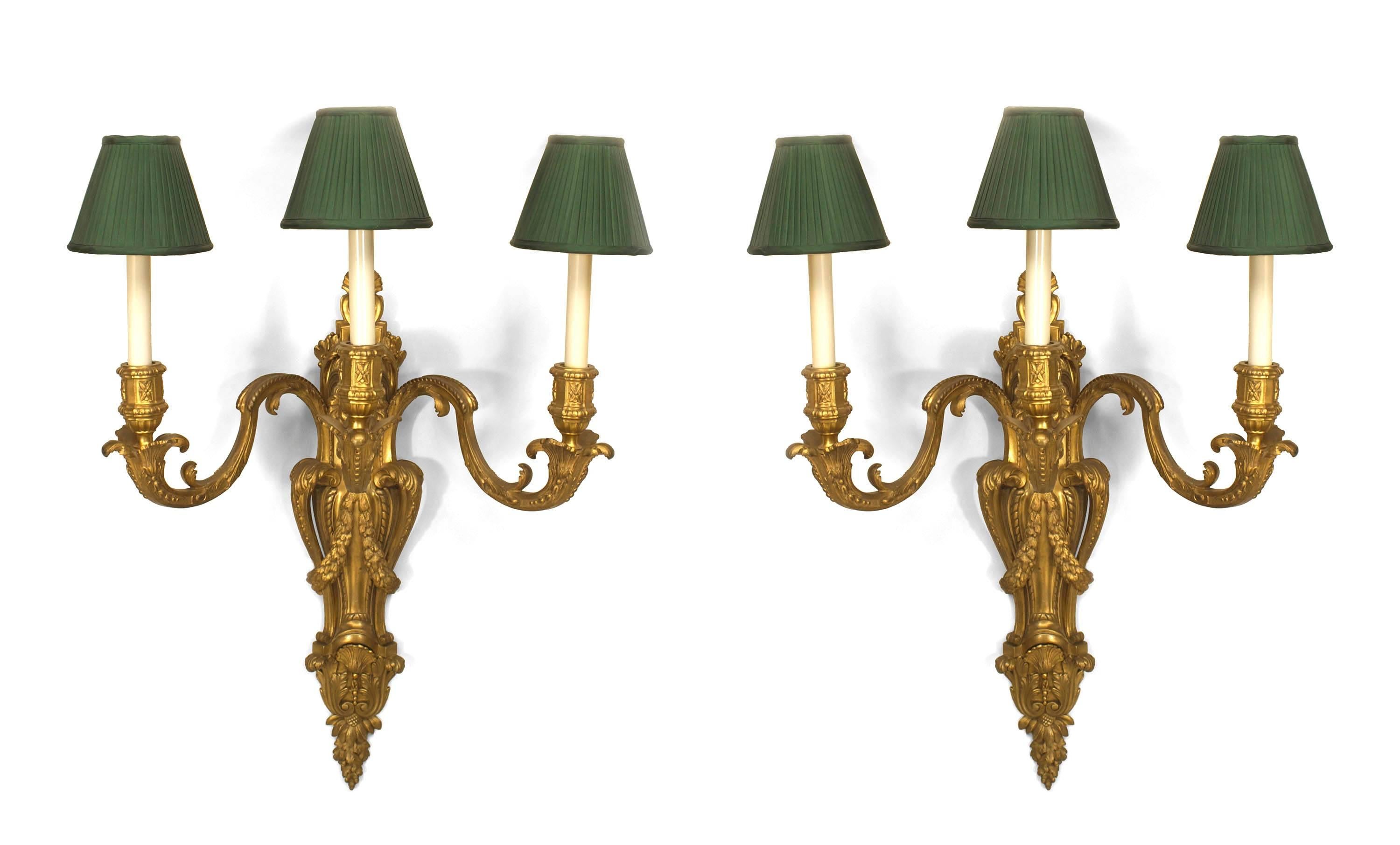 Pair of Louis XV-style (19/20th Century) bronze wall sconces with three scroll arms, a centered lion head with swags, and green pleated fabric shades (PRICED AS Pair)
