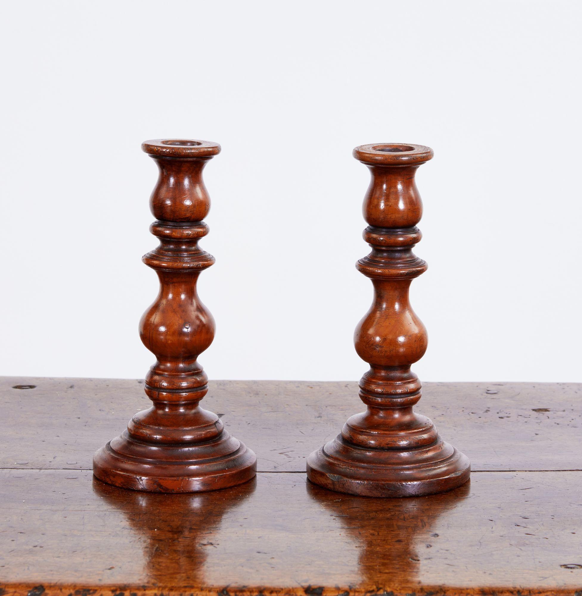 Feines Paar englischer Kerzenhalter aus gedrechseltem Obstholz des 19. Jahrhunderts in Vasen- und Reelform auf gestuften, ringförmigen Basen, mit sehr guter, reicher Farbe und Patina.