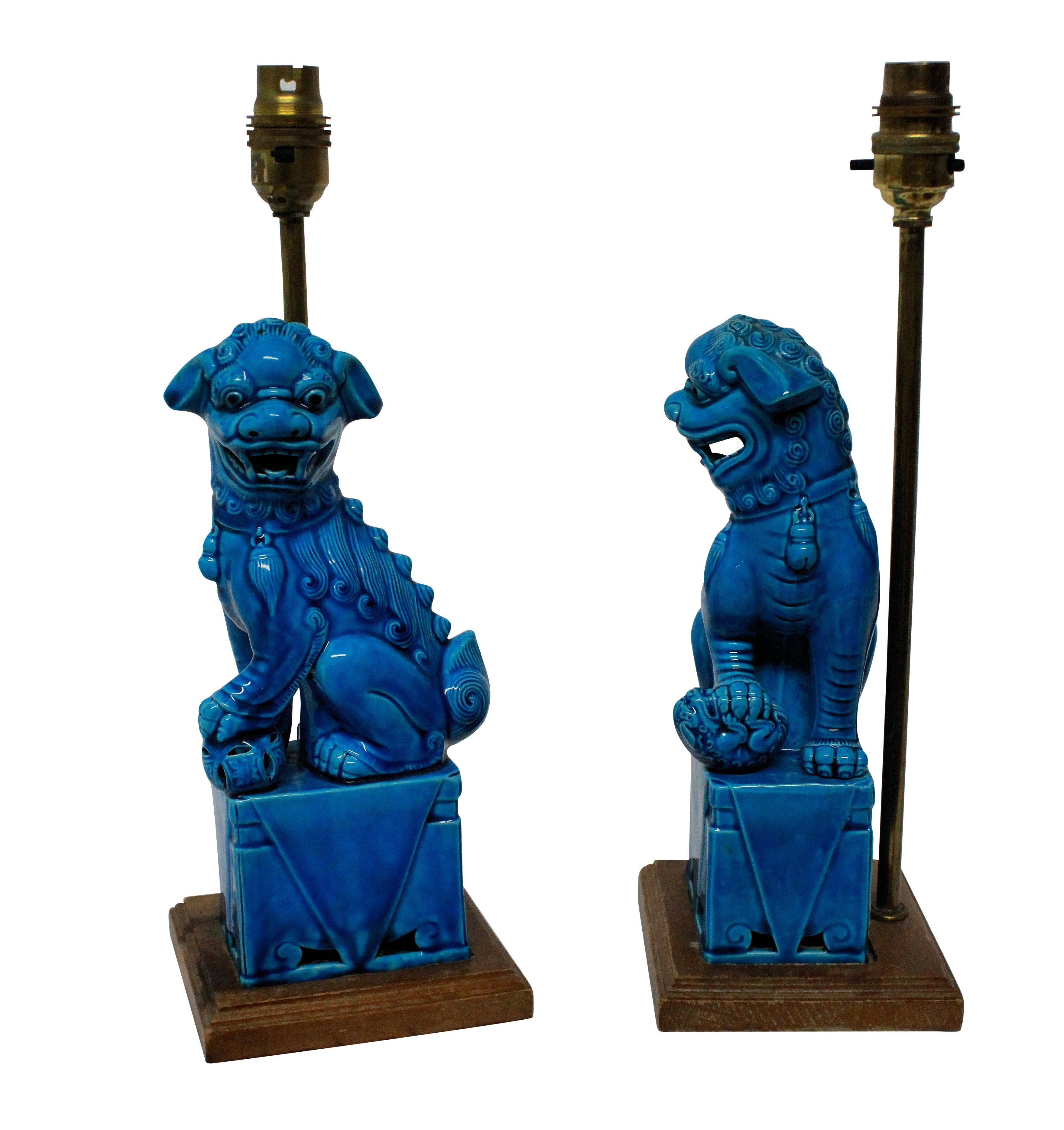 A pair of English turquoise glazed foo dogs on plinths, as lamps.