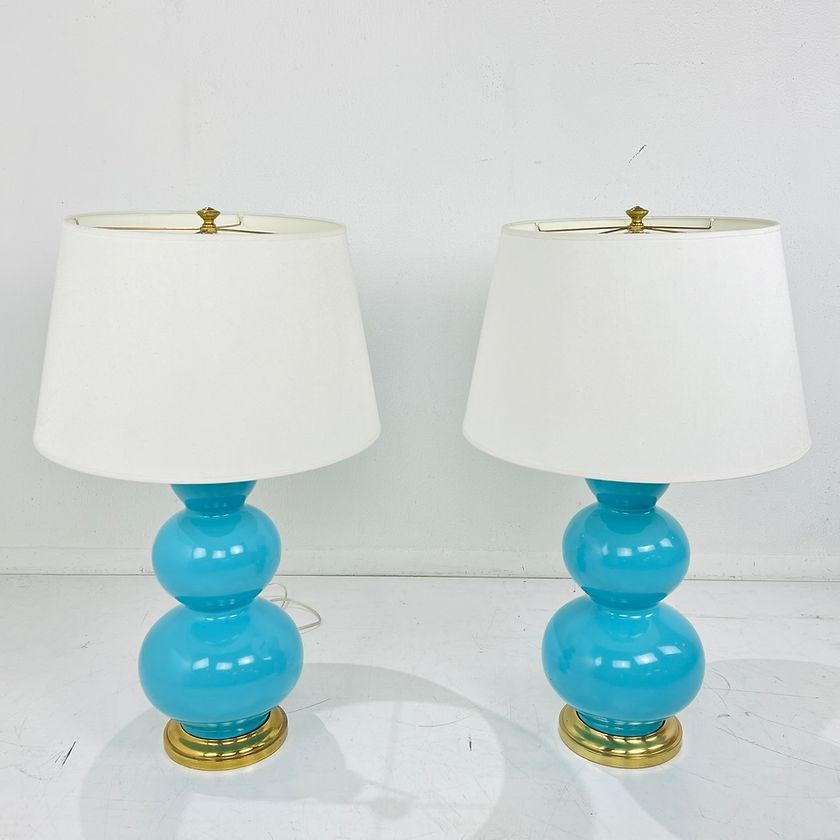 Pair of blue ceramic table lamps featuring simple but gracefully curving silhouettes with brass bases. Some patina to brass, one turn knob missing but good overall condition. Pearl Dupioni fabric Shades included. 30