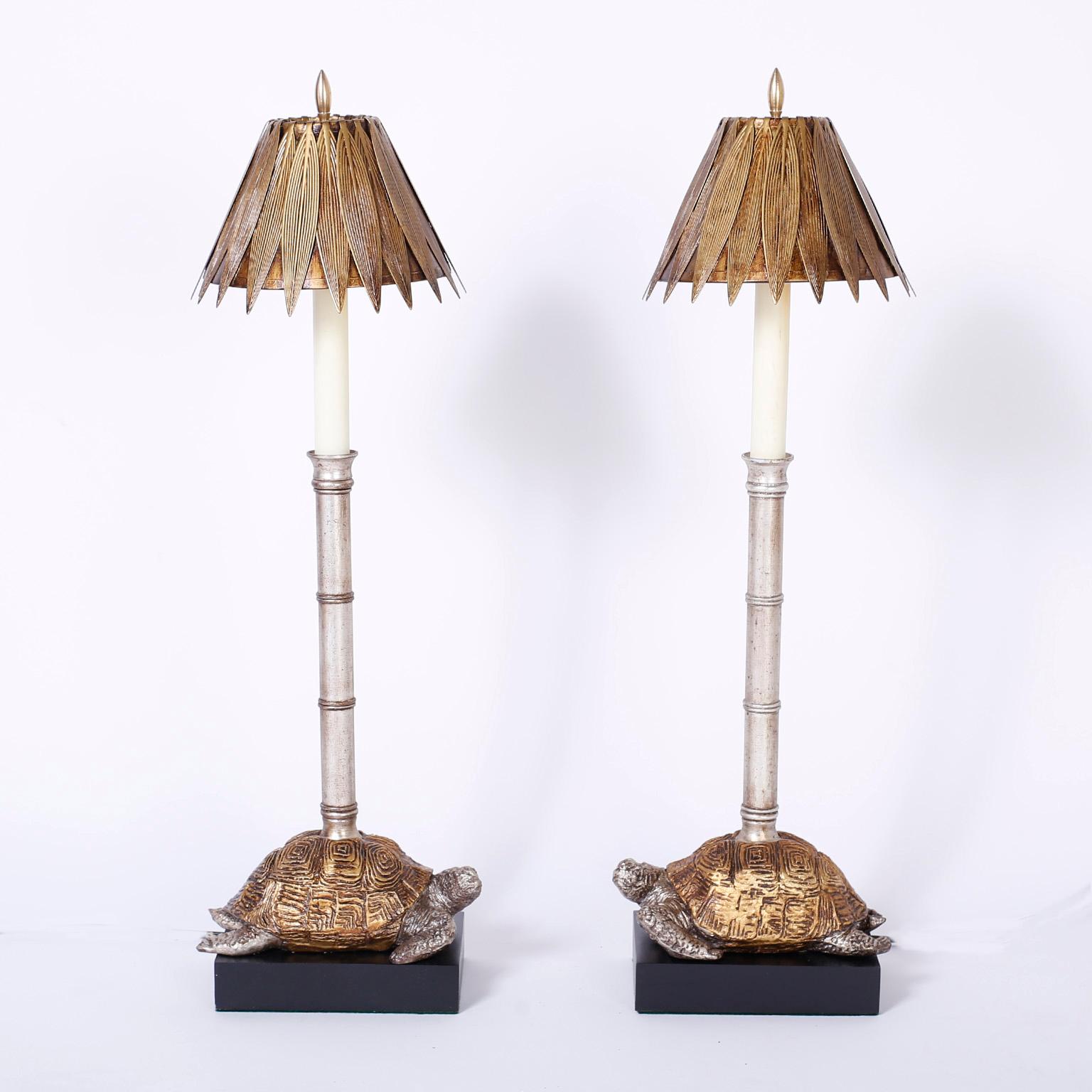 Elegant pair of table lamps with stylized brass leaf shades over faux bamboo silver leaf candlestick shafts on composition silver and gold turtles set on ebonized wood bases.