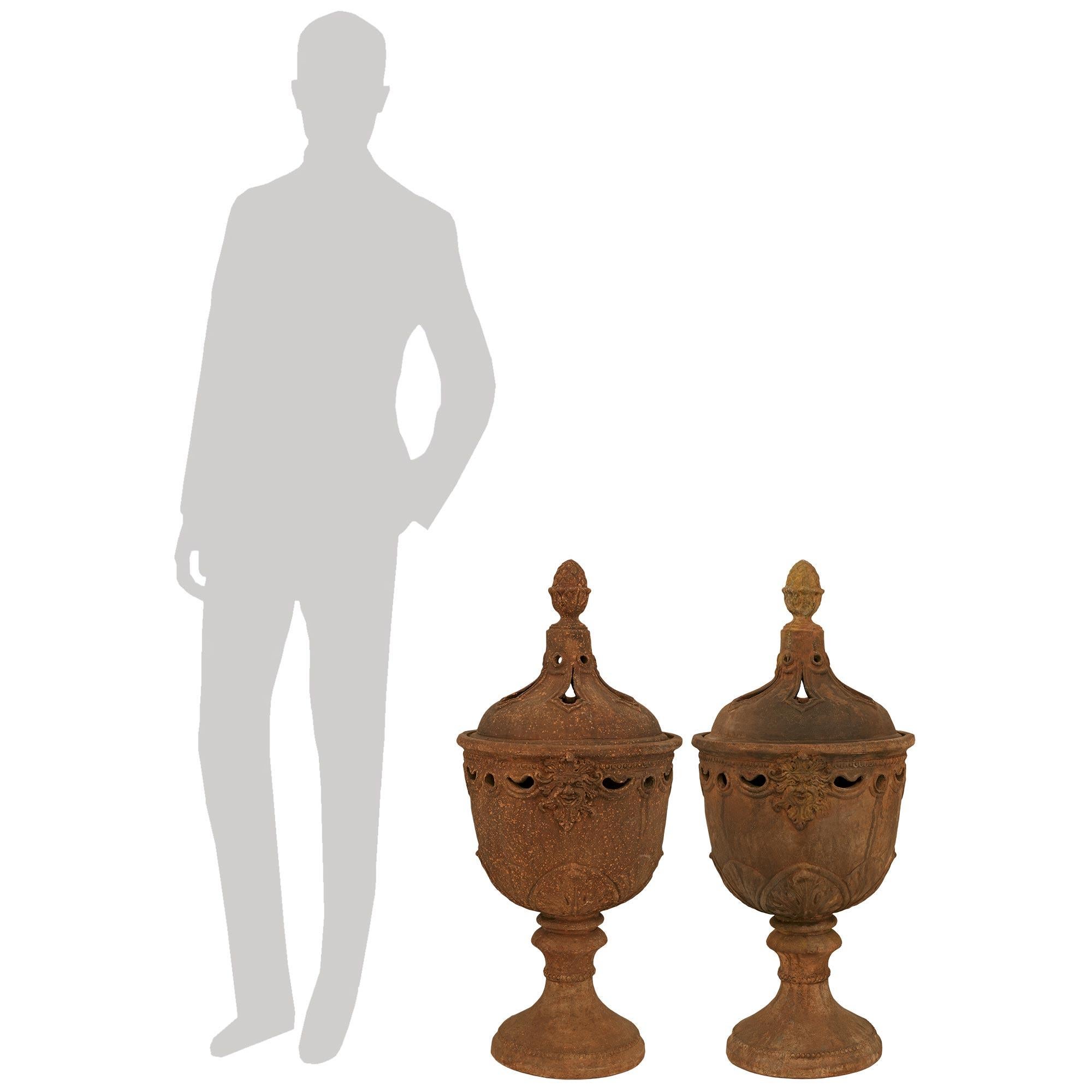 A beautiful and finely detailed pair of Tuscan early 19th century Louis XVI st. Terra Cotta urns. Each attractive Pot Pourri urn is raised on a circular socle shaped base with mottled edges. The pierced bodies display charming wrap around palmettes