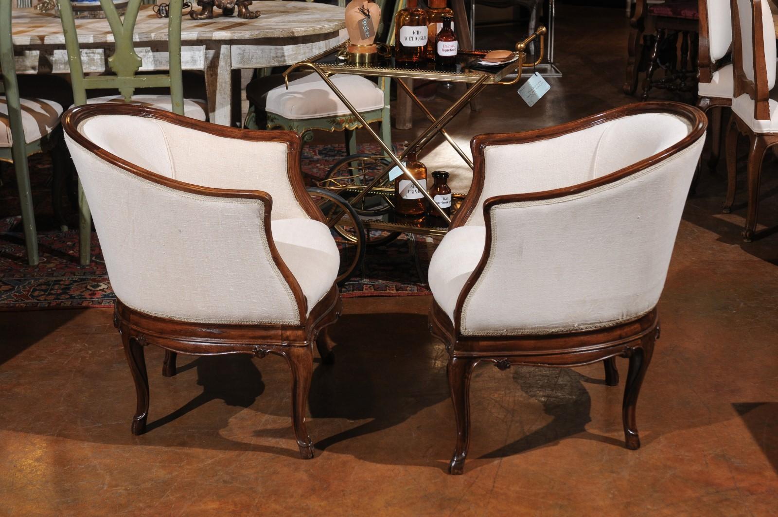 A pair of Italian Tuscan early 20th century Louis XV style club chairs from Livorno Italy, with new upholstery and cabriole legs. Born in Tuscany during the early years of the 20th century, each of this pair of Louis XV style club chairs features a