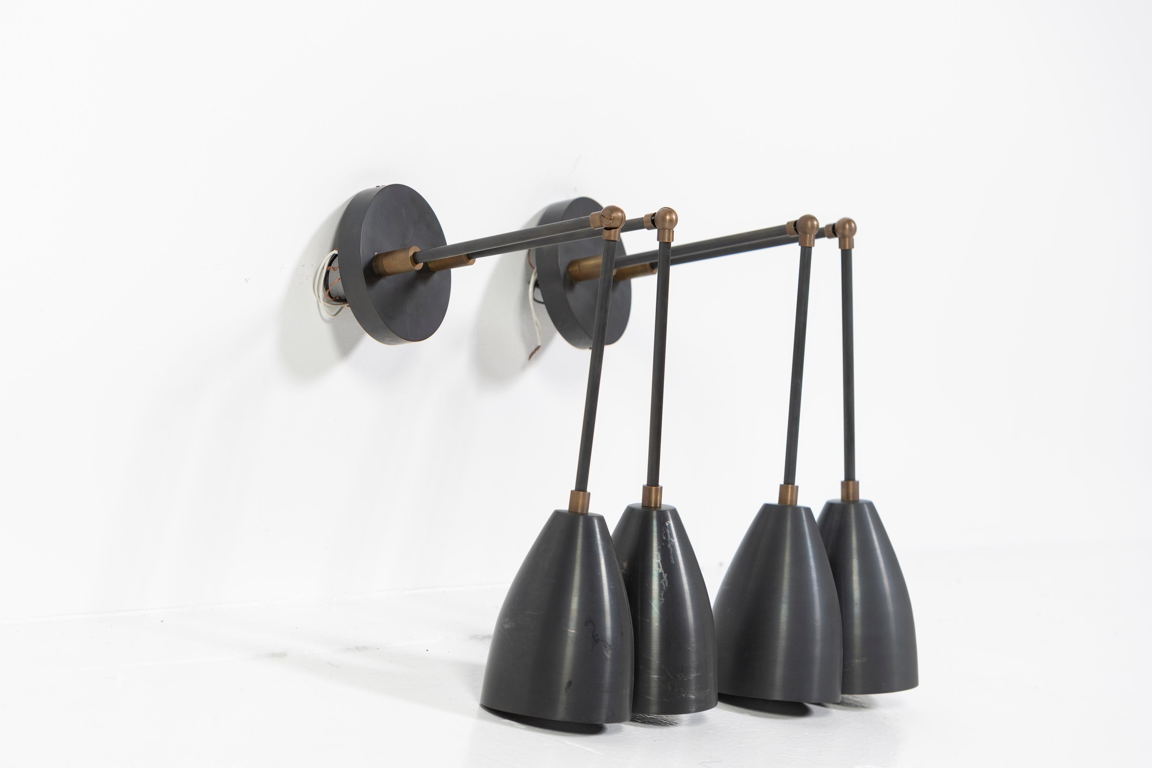 Pair of blacked brass down lights from Apparatus. Composed of linear armature with articulated connections and brass shades provide beautiful directional light.  Good pre-owned condition, ready to install, some small scratches on the shades. 