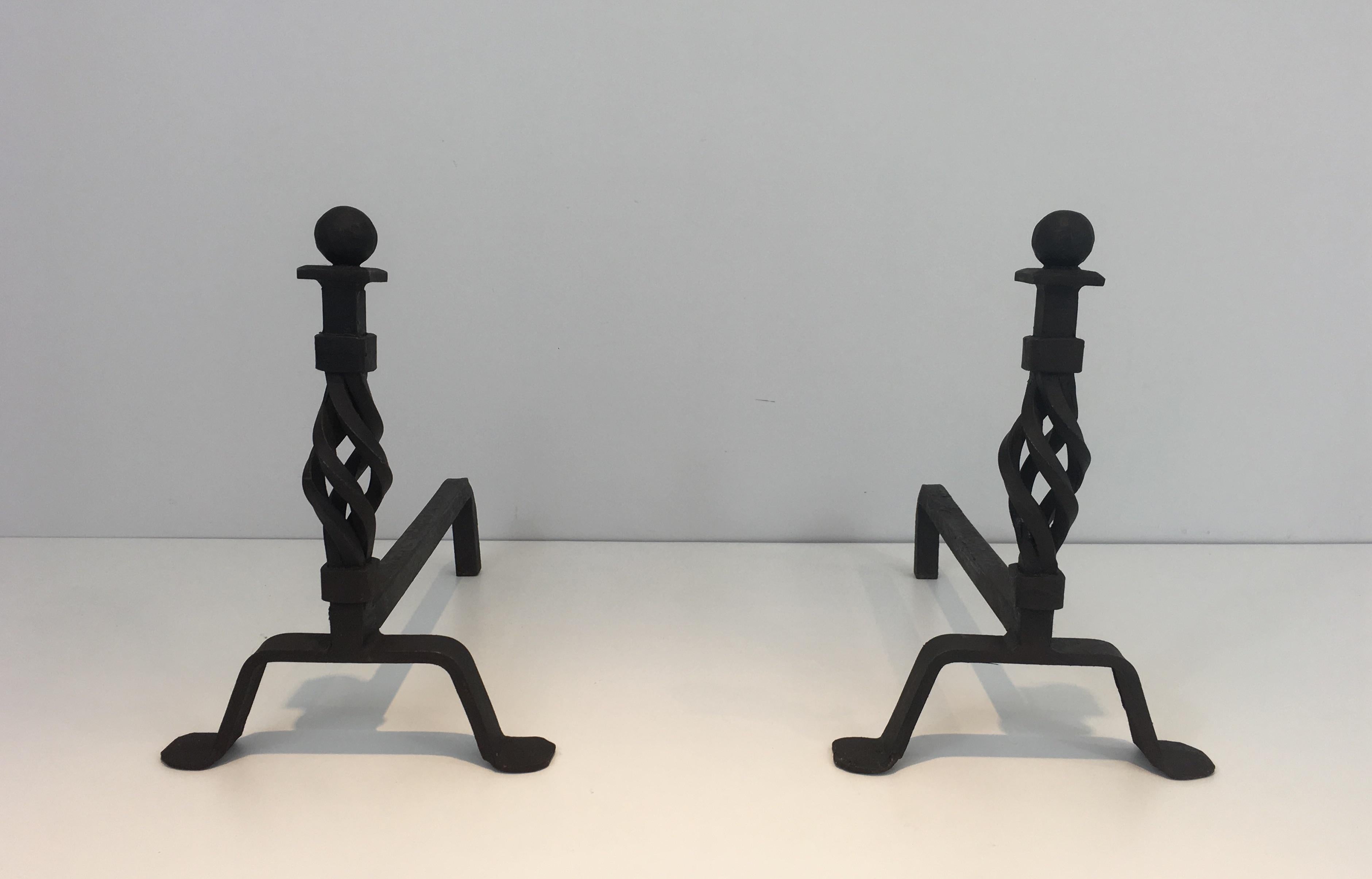 This pair of andirons is made of a twisted main part with ball on top. With their look, they can both be used for an old fire place as for a contemporary one. They are French, circa 1940