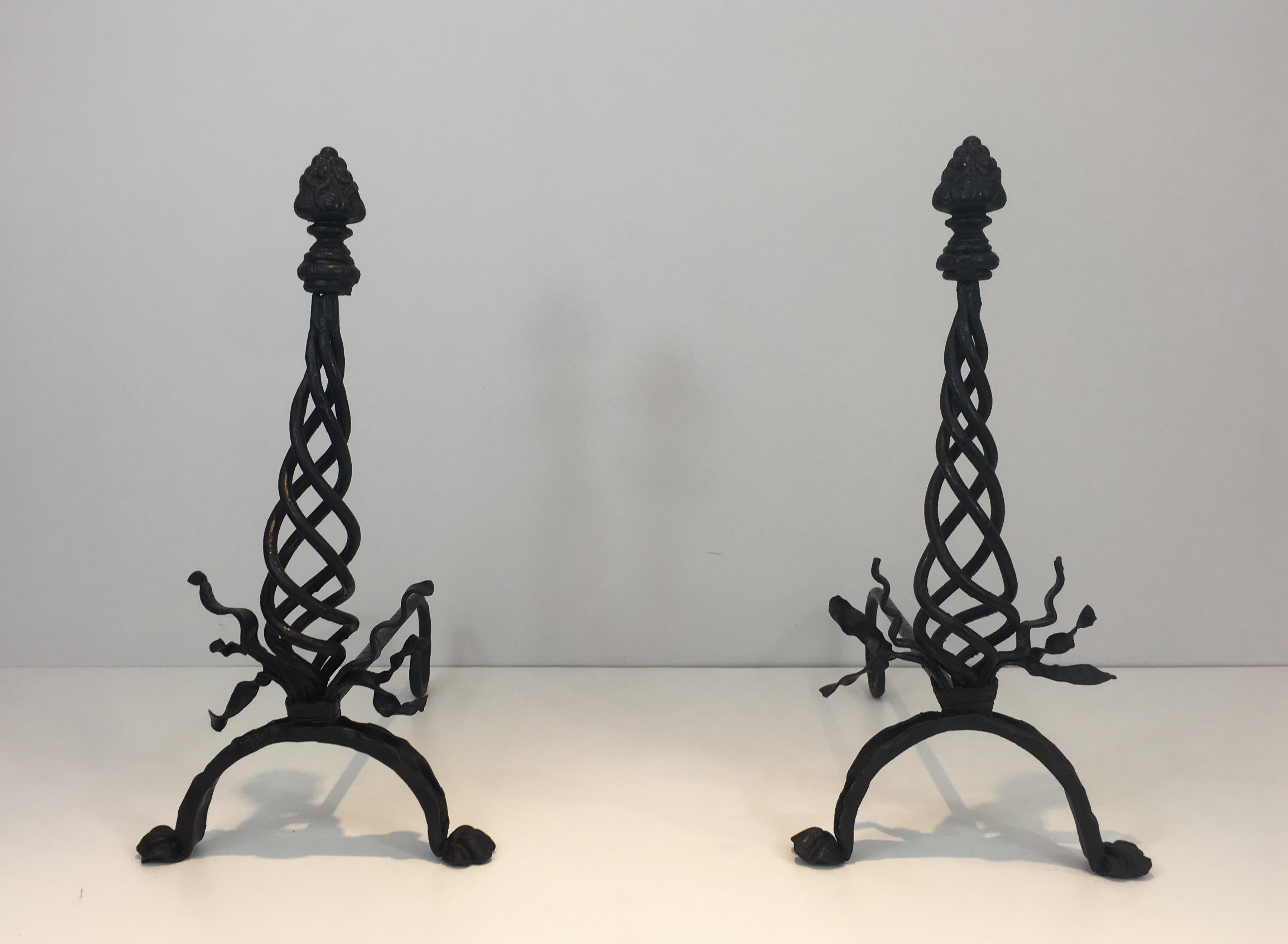 This pair of wrought iron andirons is made of a twisted central part with ribbons on the base and a large finial on top. They are French, circa 1920.