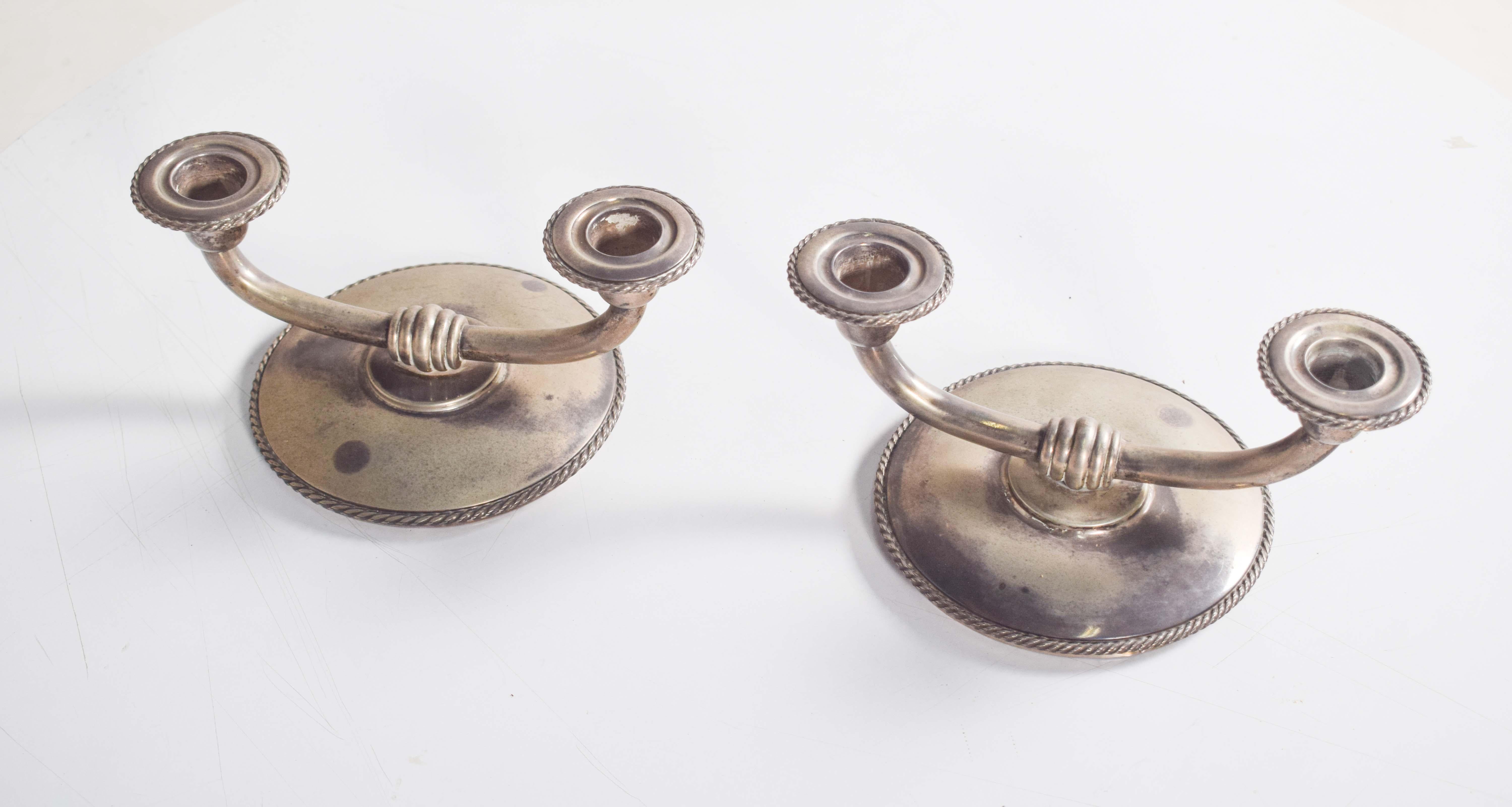 Una splendida coppia di candelabri a due bracci, realizzati in argento portoghese marcato e di squisita fattura. Ogni candelabro è dotato di una base rotonda e di un portacandele, impreziositi da un'intricata decorazione a tortiglione. Il design