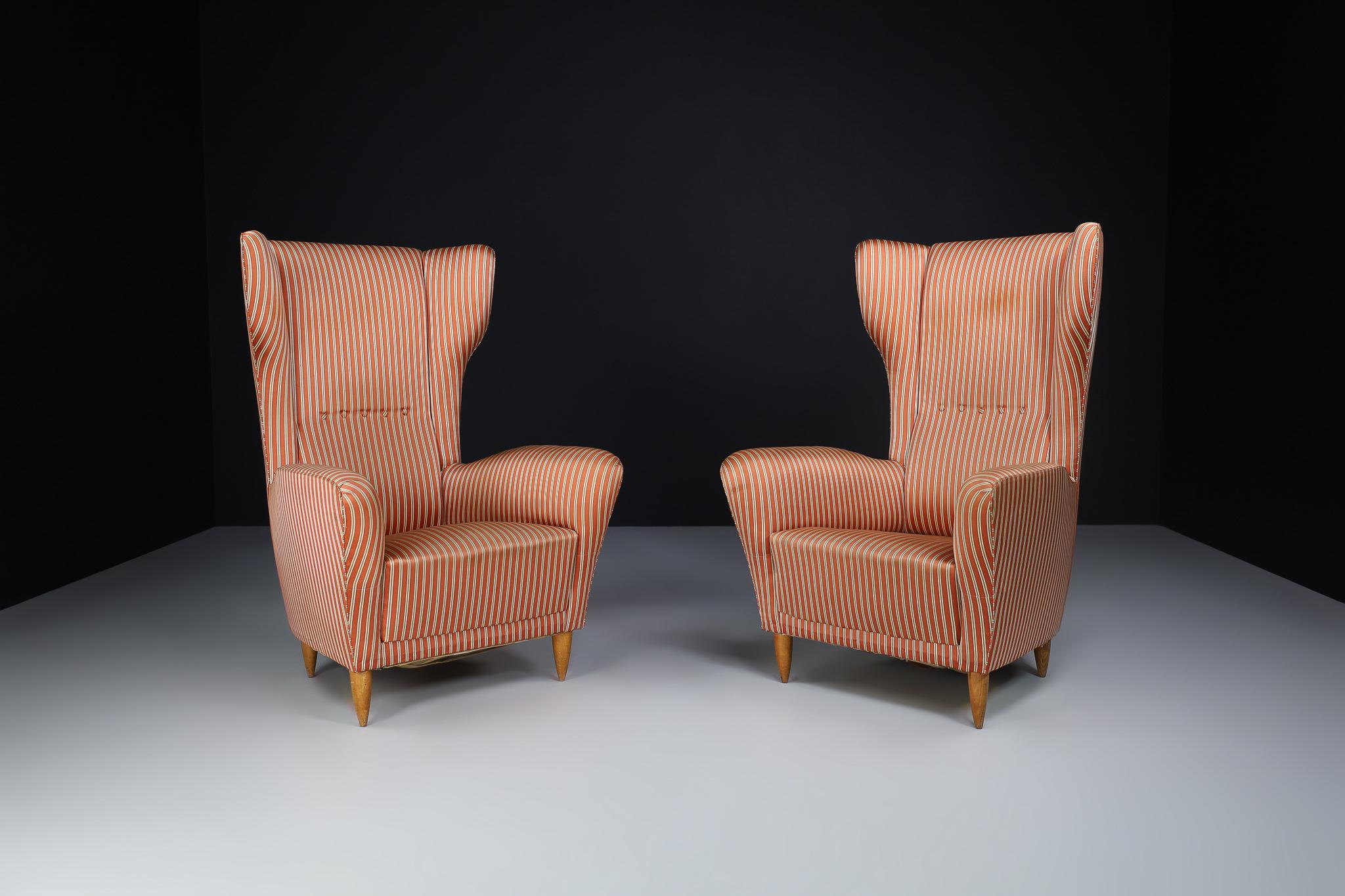 Pair of original high back lounge chairs made and designed in the style of Federico Munari and Gio Ponti in Italy 1940s. This elegant set of lounge chairs features wings and curved armrests. Thanks to its elegant armrests and seating, the chair gets