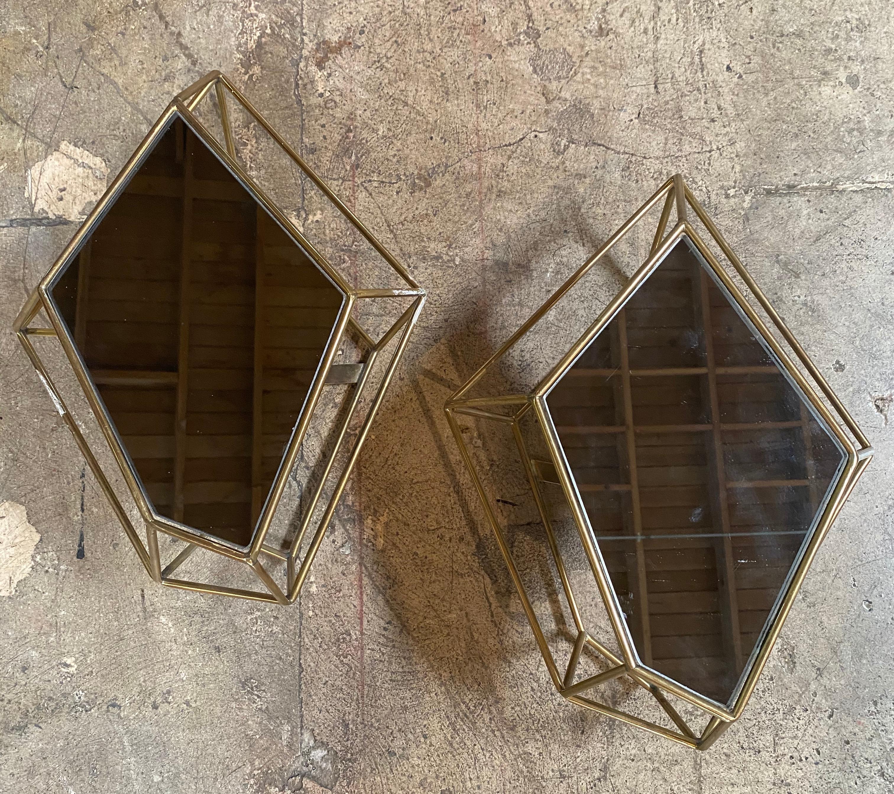 Stunning pair of two sculptural light wall sconces in brass and mirror, Italy, 1970s.
The sconces have an extraordinary sculptural design created with brass and a glass that rests on the upper part of the sconces, an iconic piece that will complete