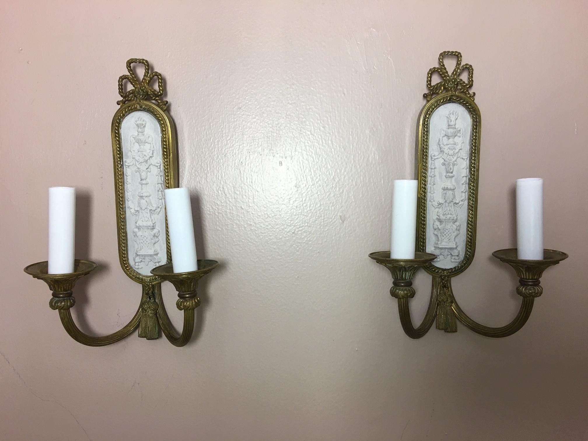 Pair of two light brass ribbon top sconces with painted back, 20th century.