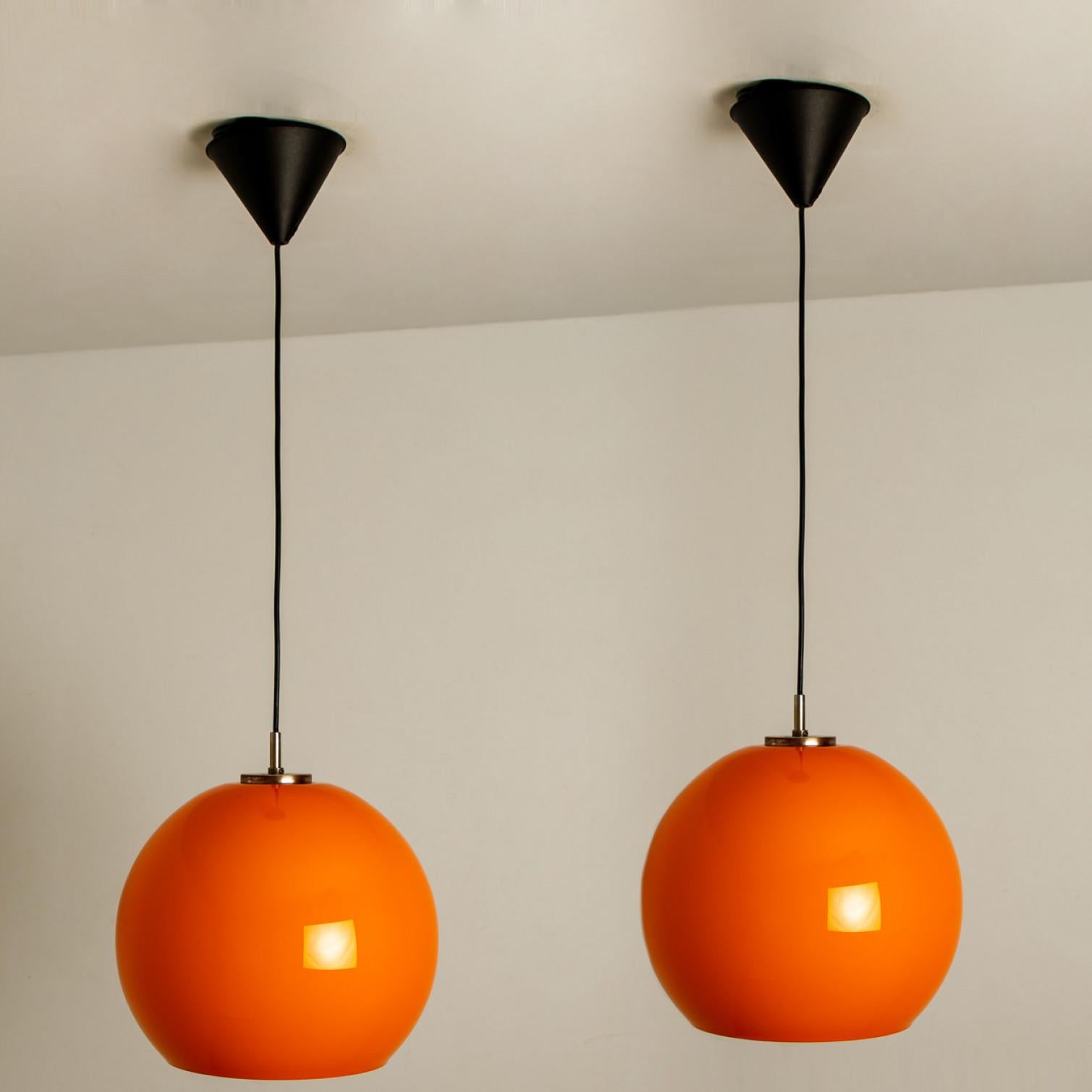 There’s something about orange that screams this particular era. And this 1970s pair of Peill & Putzler ceiling pendant lamps is very orange!
With a white or black cord and canopy.

The lovely hand blown lampshade is made of a ‘cast opaque orange