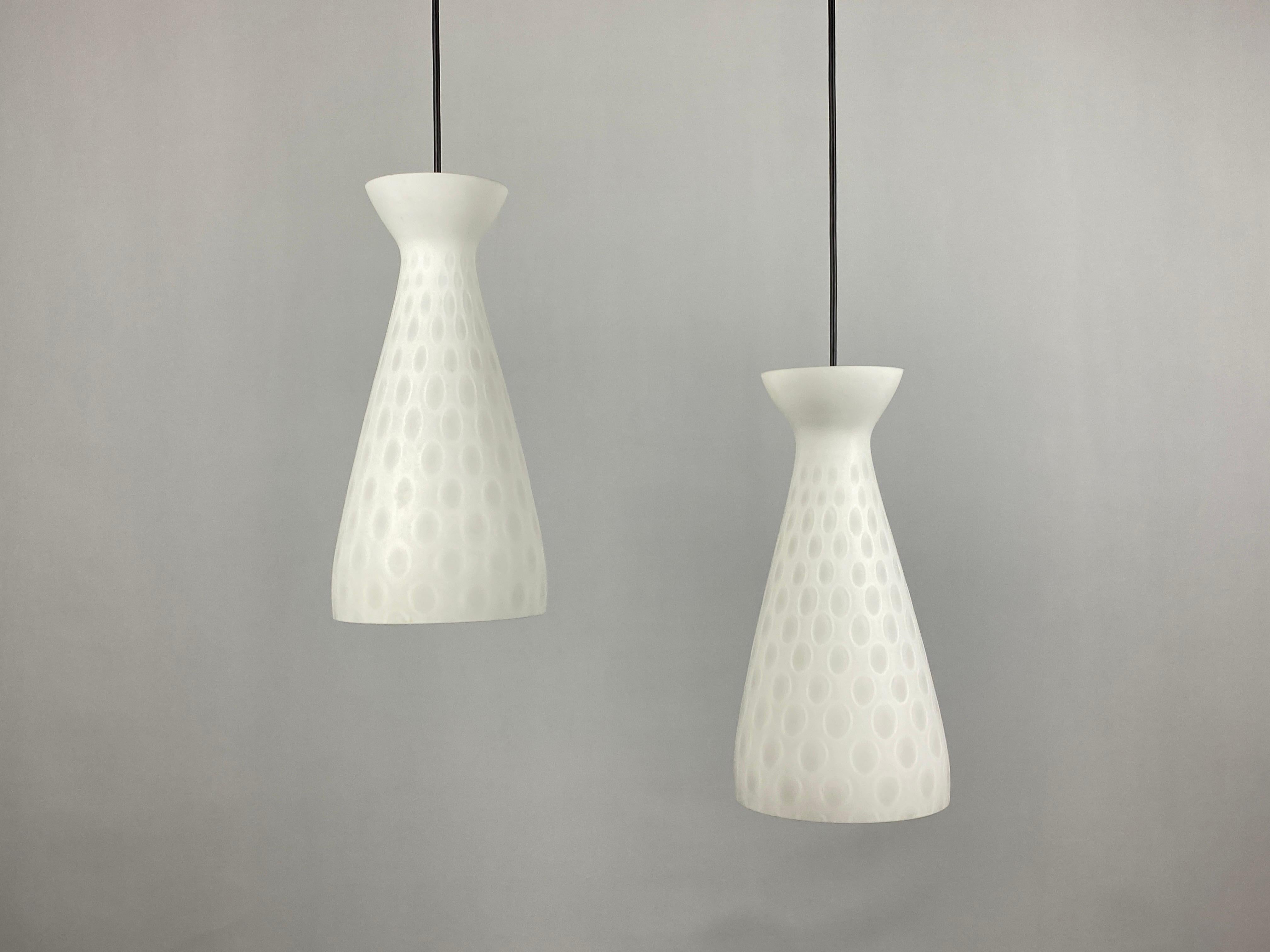 A pair of milky white glass pendant lights designed by Aloys Gangkofner for the high-quality glass factory Peill and Putzler from the 1960s. This model is called Ibiza.

Has a very interesting pattern and diabolo like shape. I have a mushroom table